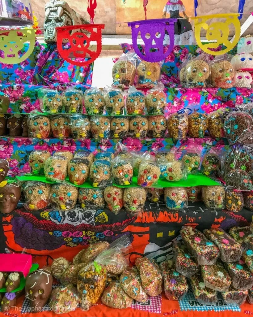 Colorful display of traditional Mexican sugar skulls and confections at a Day of the Dead celebration.