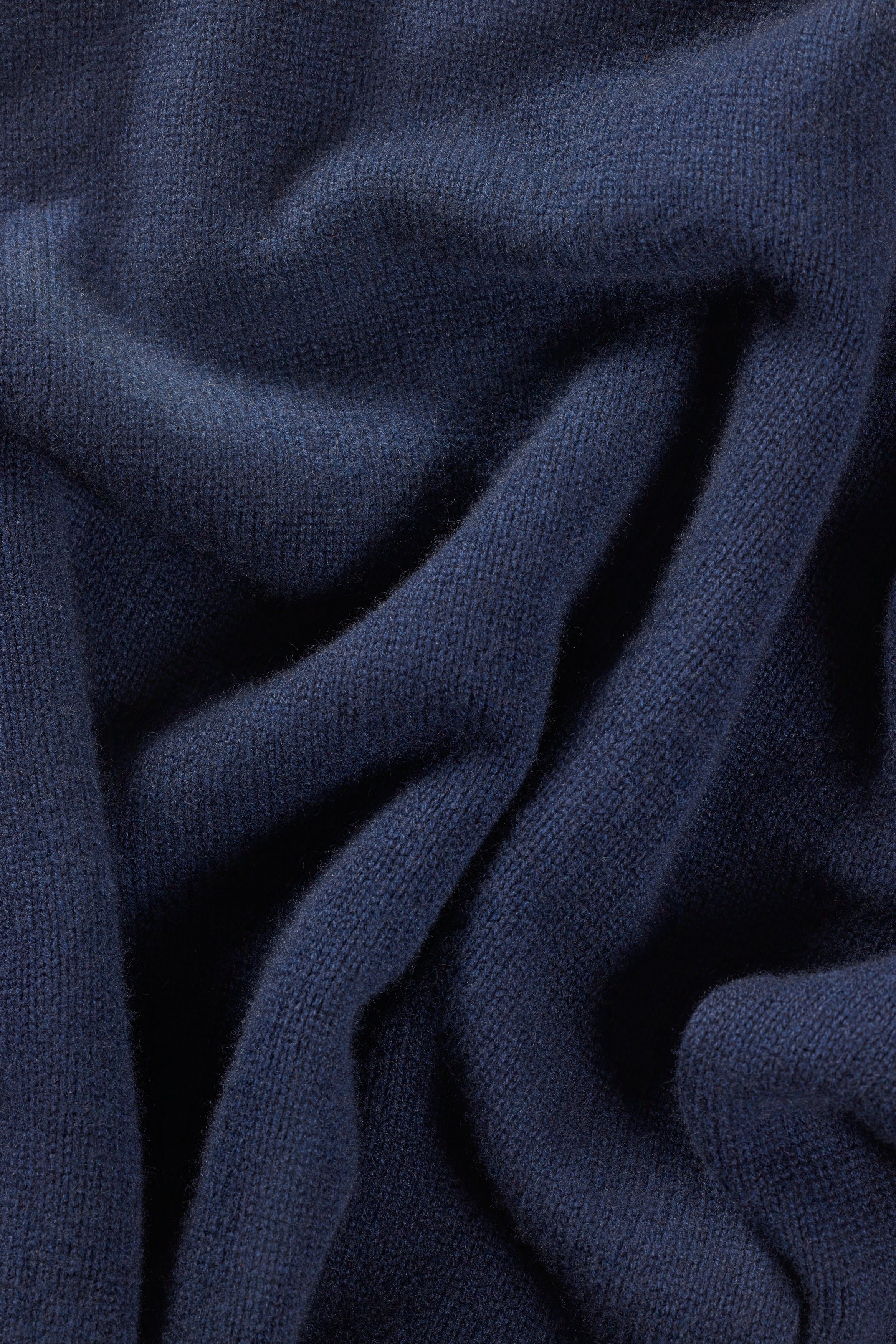 Close-up of dark blue fabric with soft texture and draped folds.