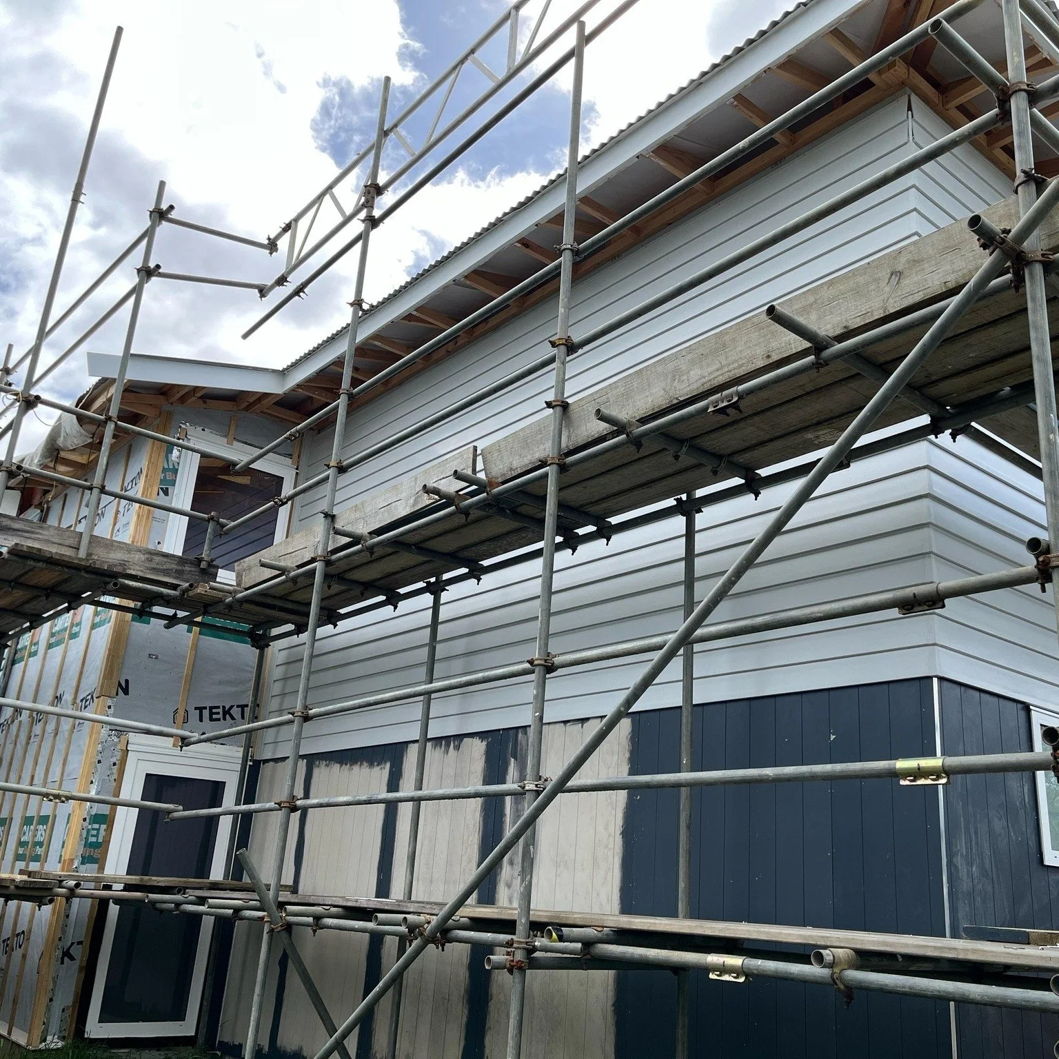 Construction scaffolding around a house under renovation or building.