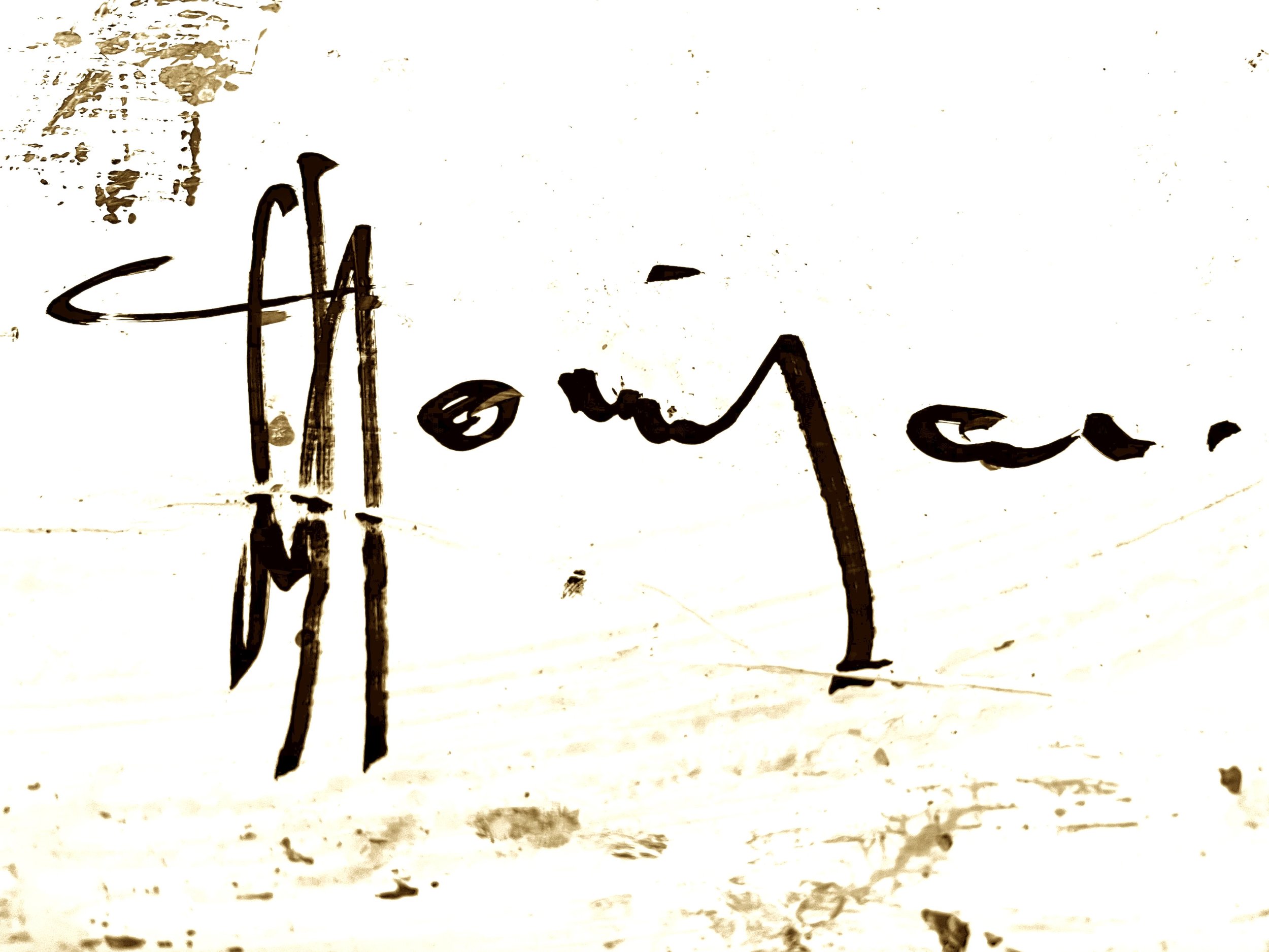 A white wall with black handwritten signature of the artist