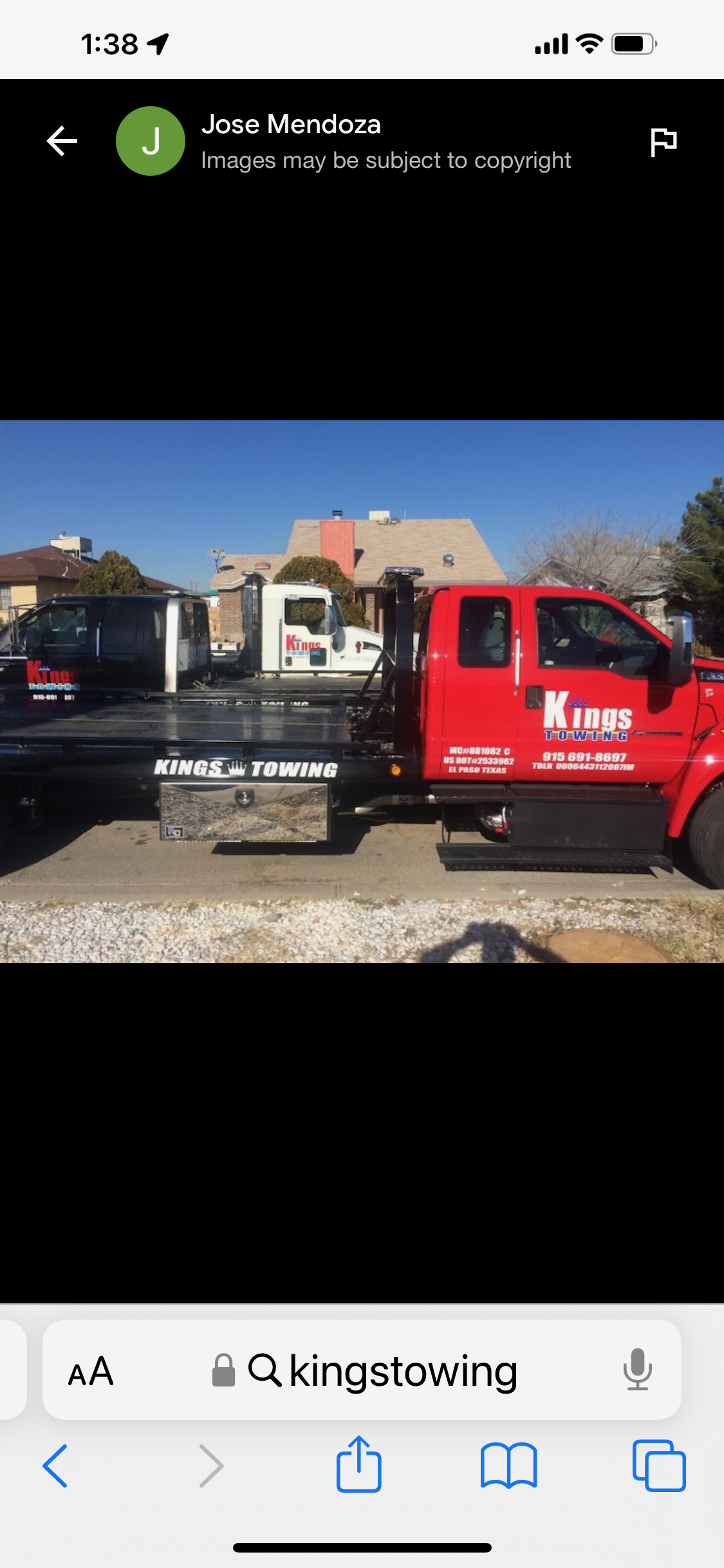 Red tow truck with black flatbed and 'Kings Towing' logo parked on the street, with house and trees in the background.