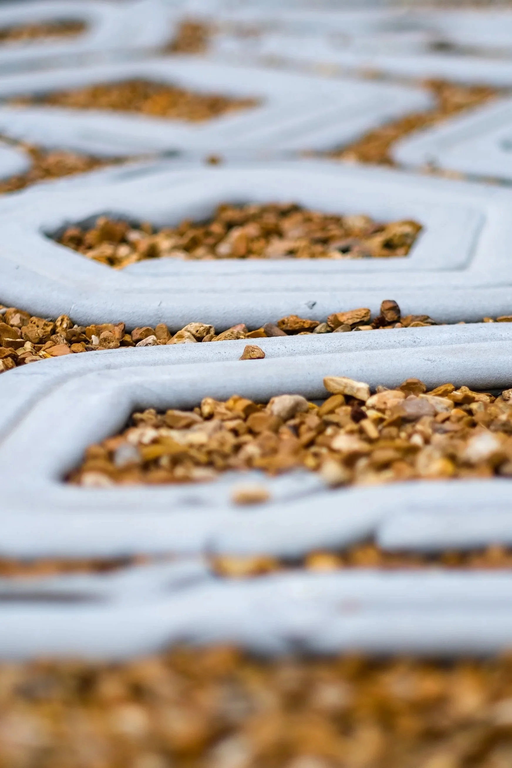 Close-up of a textured surface with a pattern of white frame beds filled with small brown rocks or gravel.
