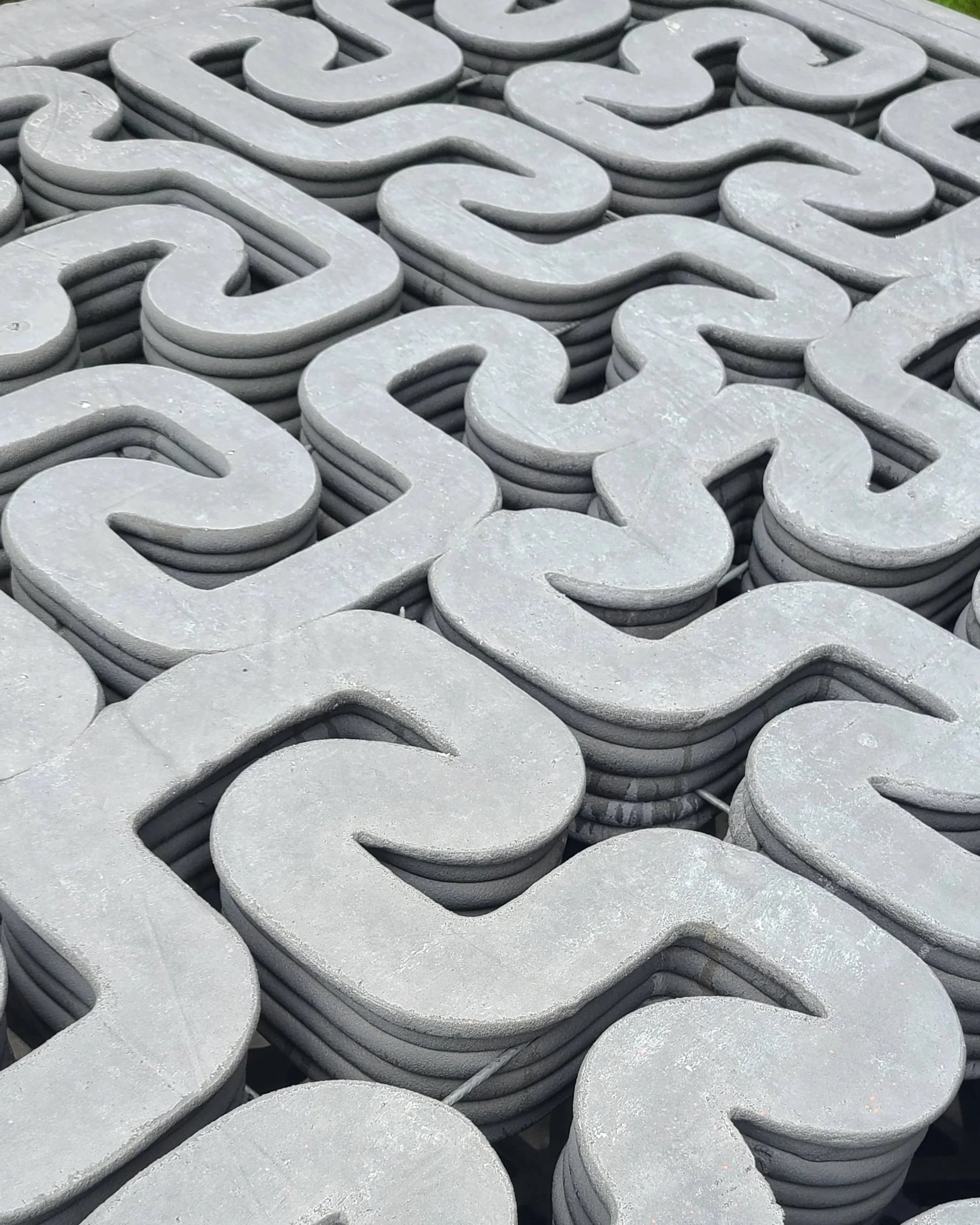 Close-up of stacked gray concrete decorative S-shaped pieces.