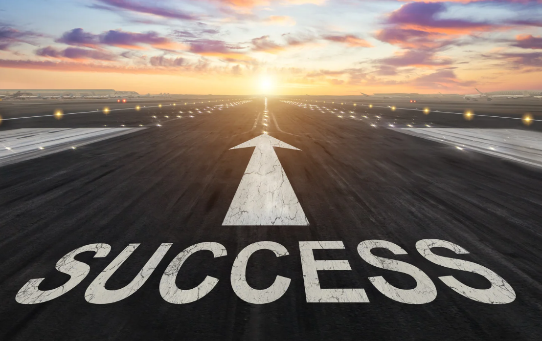 A runway at sunset with the word 'Success' written on it and an arrow pointing forward, symbolizing progress and achievement.