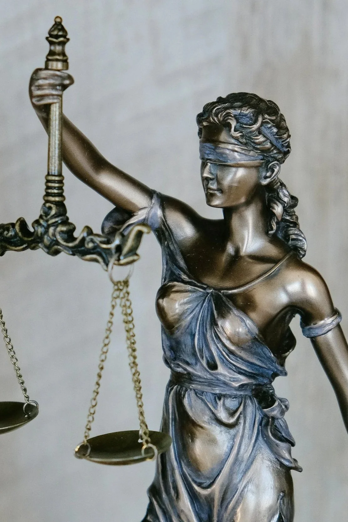 A detailed bronze statue of Lady Justice holding scales, with her eyes blindfolded.
