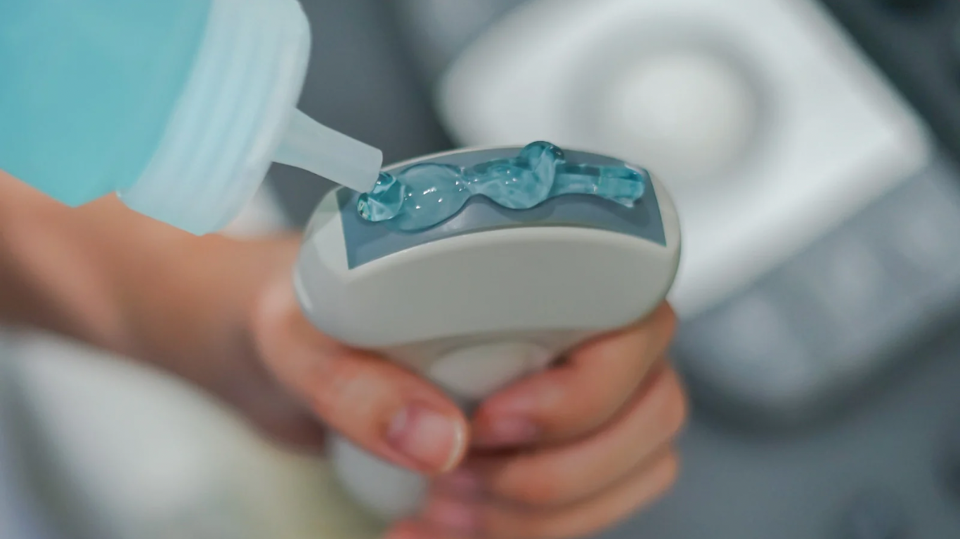 A person holding an Invisalign aligner with blue dental adhesive being applied.