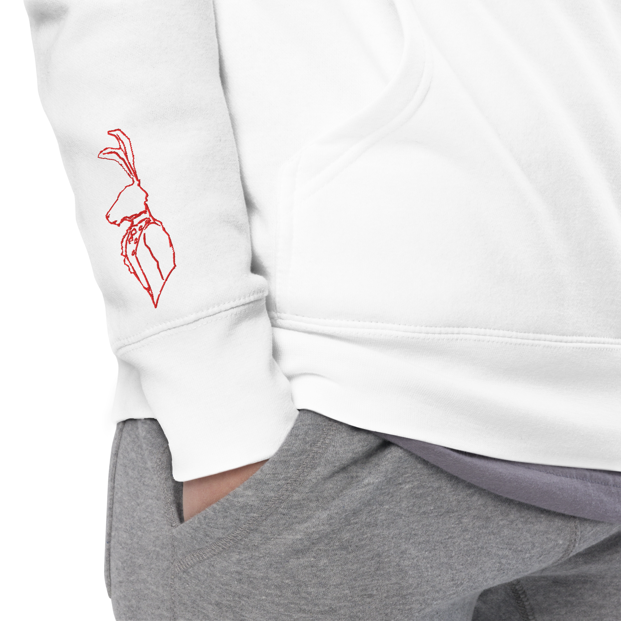 Close-up of a person wearing a white sweatshirt with a red embroidered hare on the sleeve and gray sweatpants, with their hand in the pocket.