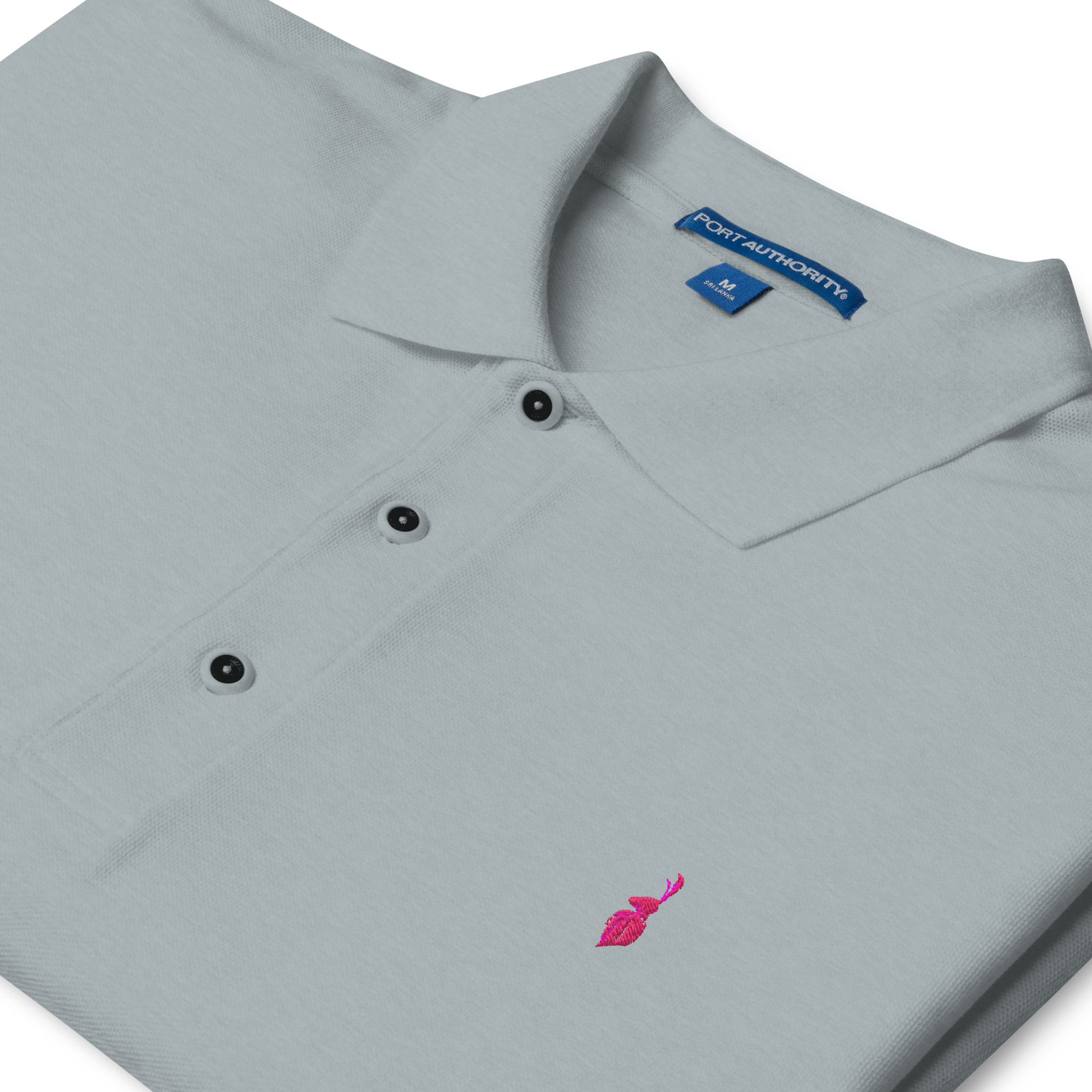 Close-up of a white polo shirt with a pink embroidered flamingo logo on the lower left side and three black and white buttons on the placket.