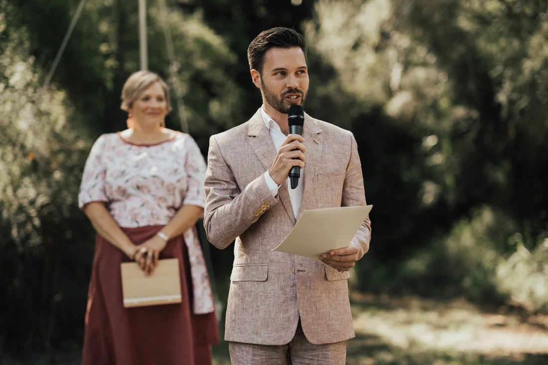 Dee Wild Celebrant looks on smiling as a guest delivers part of a wedding ceremony.