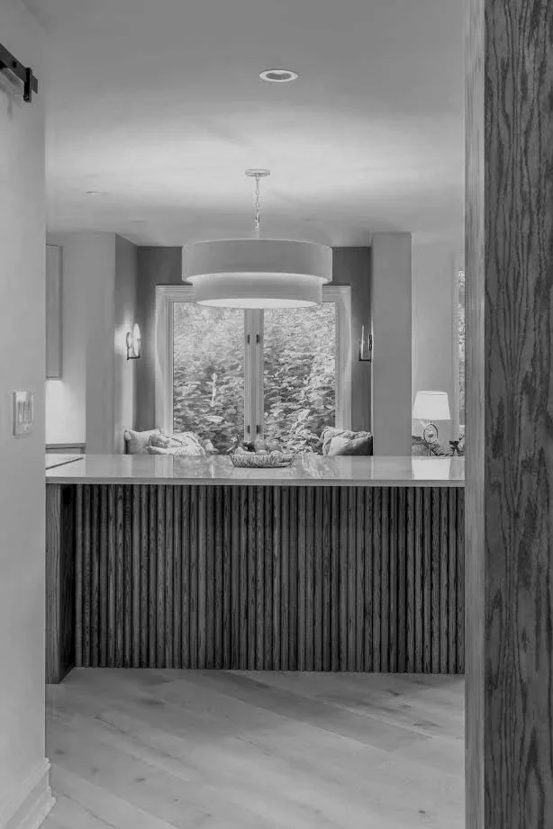 A cozy kitchen with a view of a window and a sitting area with cushions, decorated with lamps and a modern pendant light.