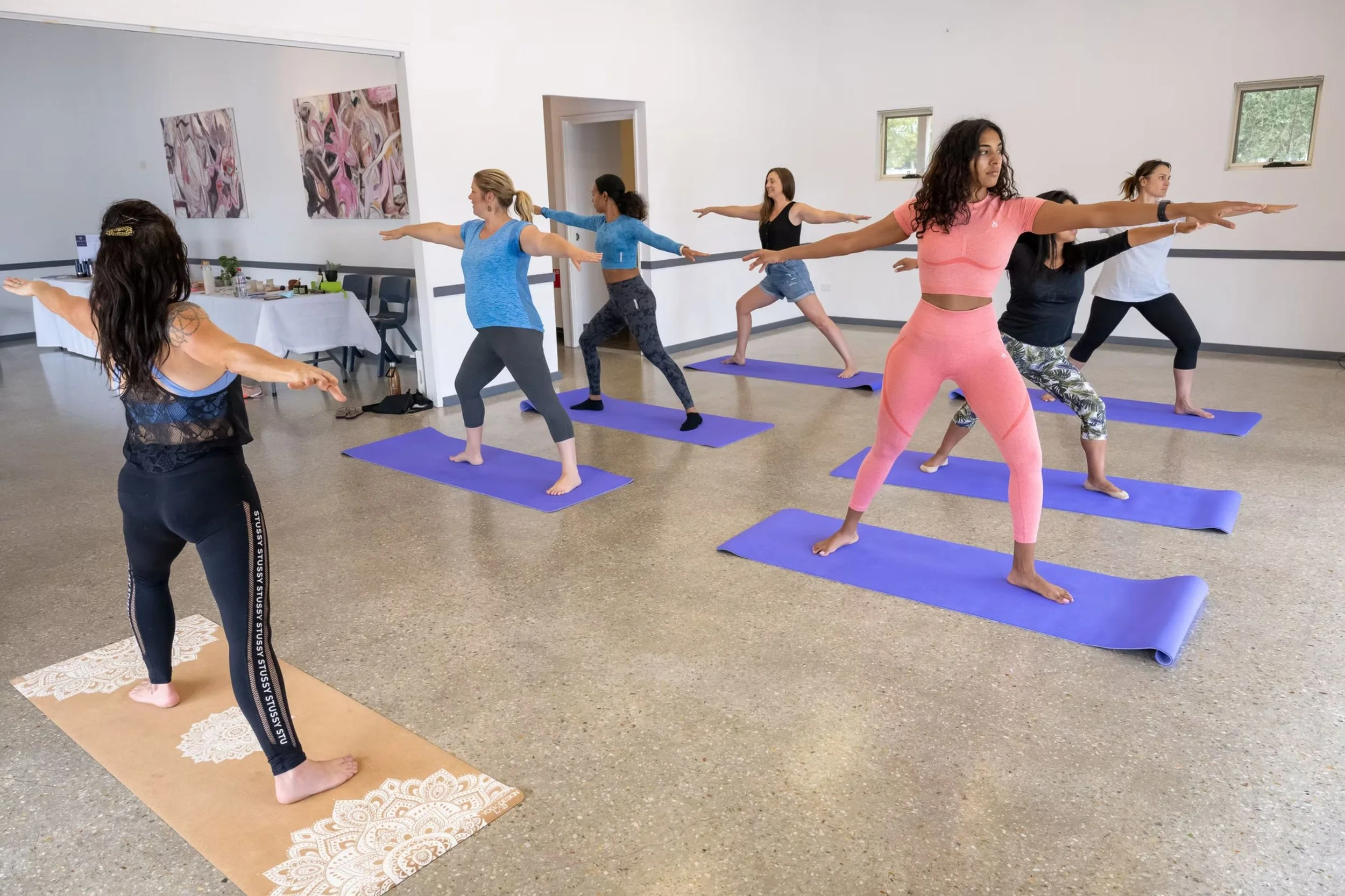 ID: A yoga class. The instructor and participants stand on mats.