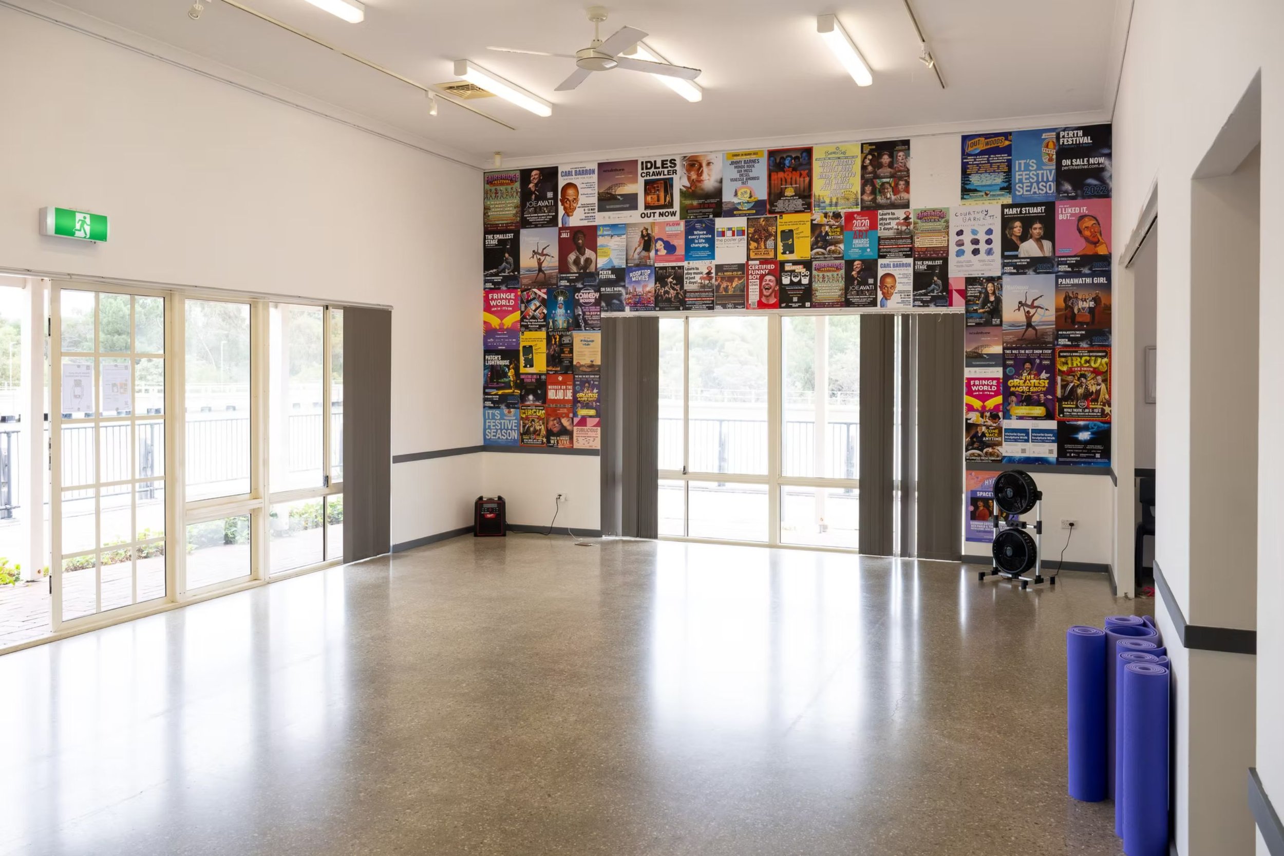ID: An inside view of The Grapevine. Posters cover the wall opposite to the viewer. Natural light fills the room through large windows.