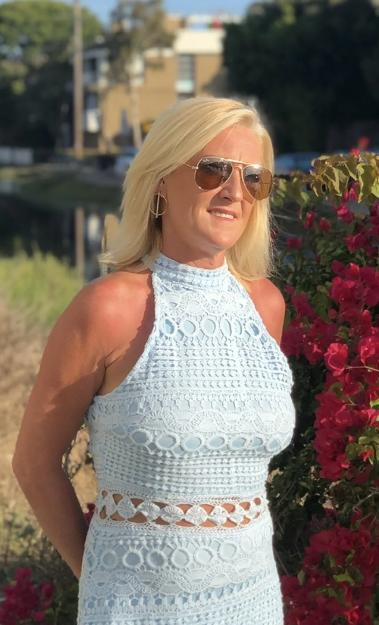 Colleen Conway outdoors in a pale-blue dress beside flowering bougainvillea in warm evening light.