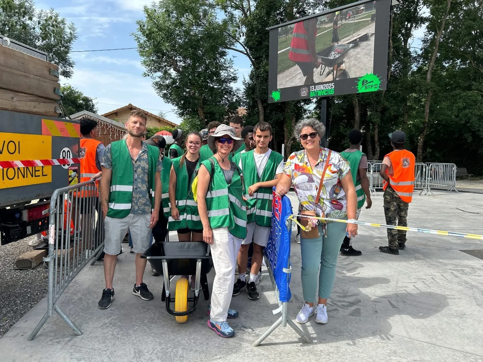 Une équipe en gilets verts prête pour les épreuves avec sa brouette