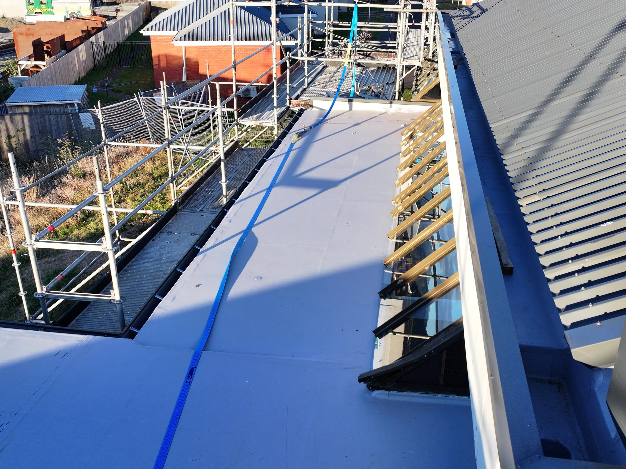 Construction scaffolding and roofing work on a building's roof with metal beams and scaffolding setup