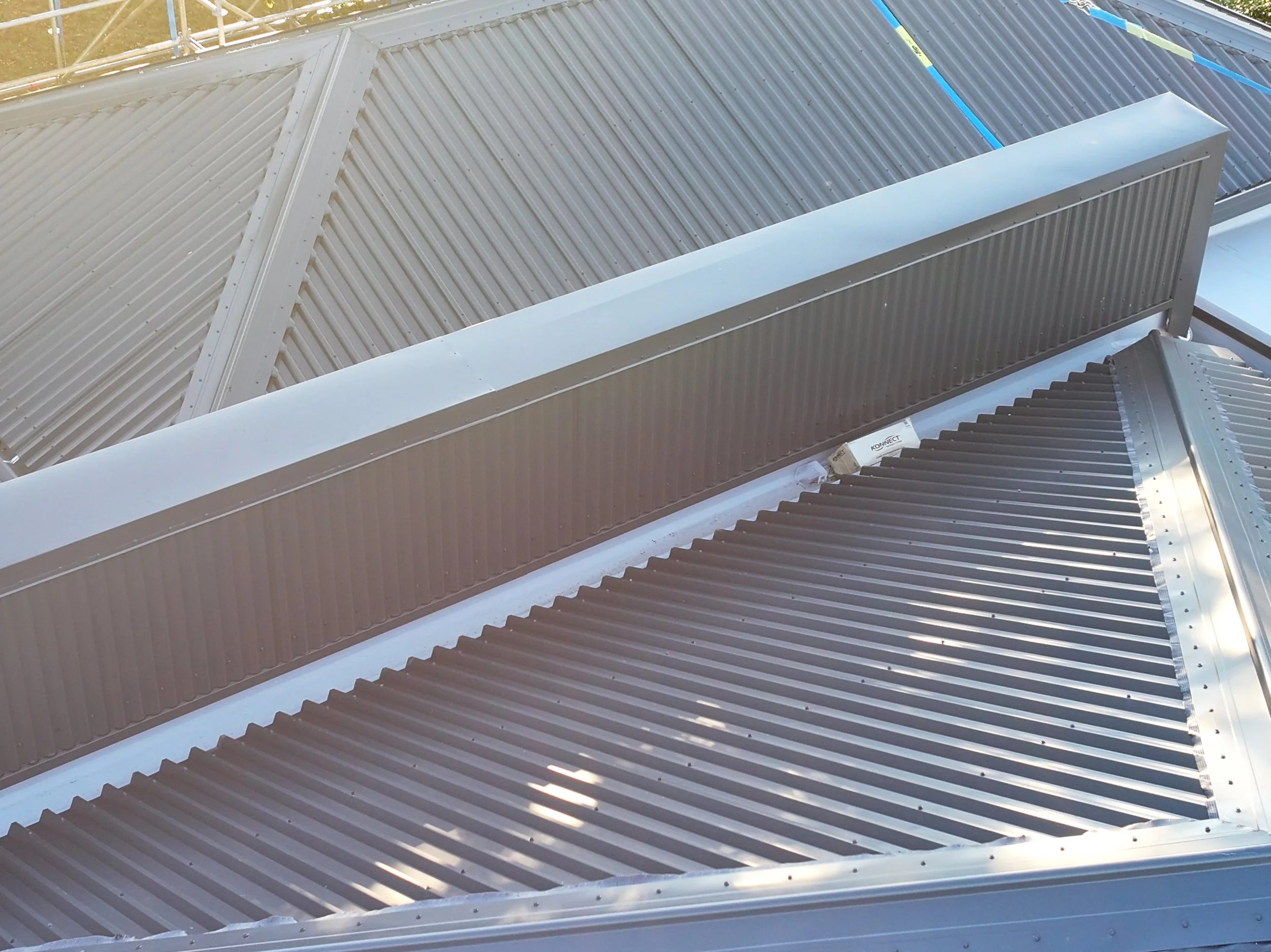 Multiple metal roofing panels and vents on a building roof