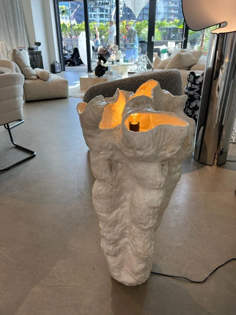 A decorative lamp that resembles a large, textured, white volcanic or rock formation with an open top and warm interior lighting inside.