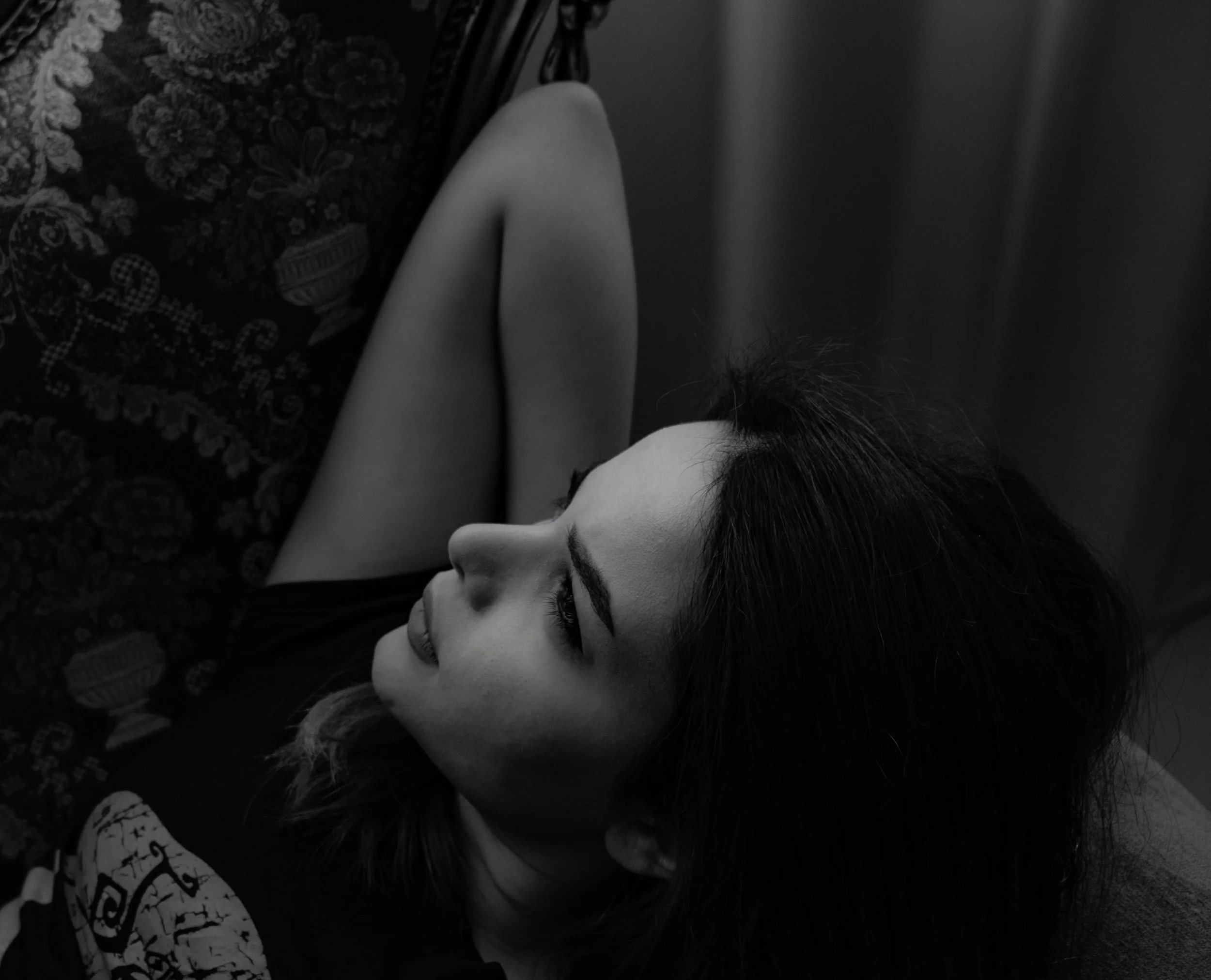 A woman lying on her side, resting her head on her arm, with her eyes closed in a relaxed pose.