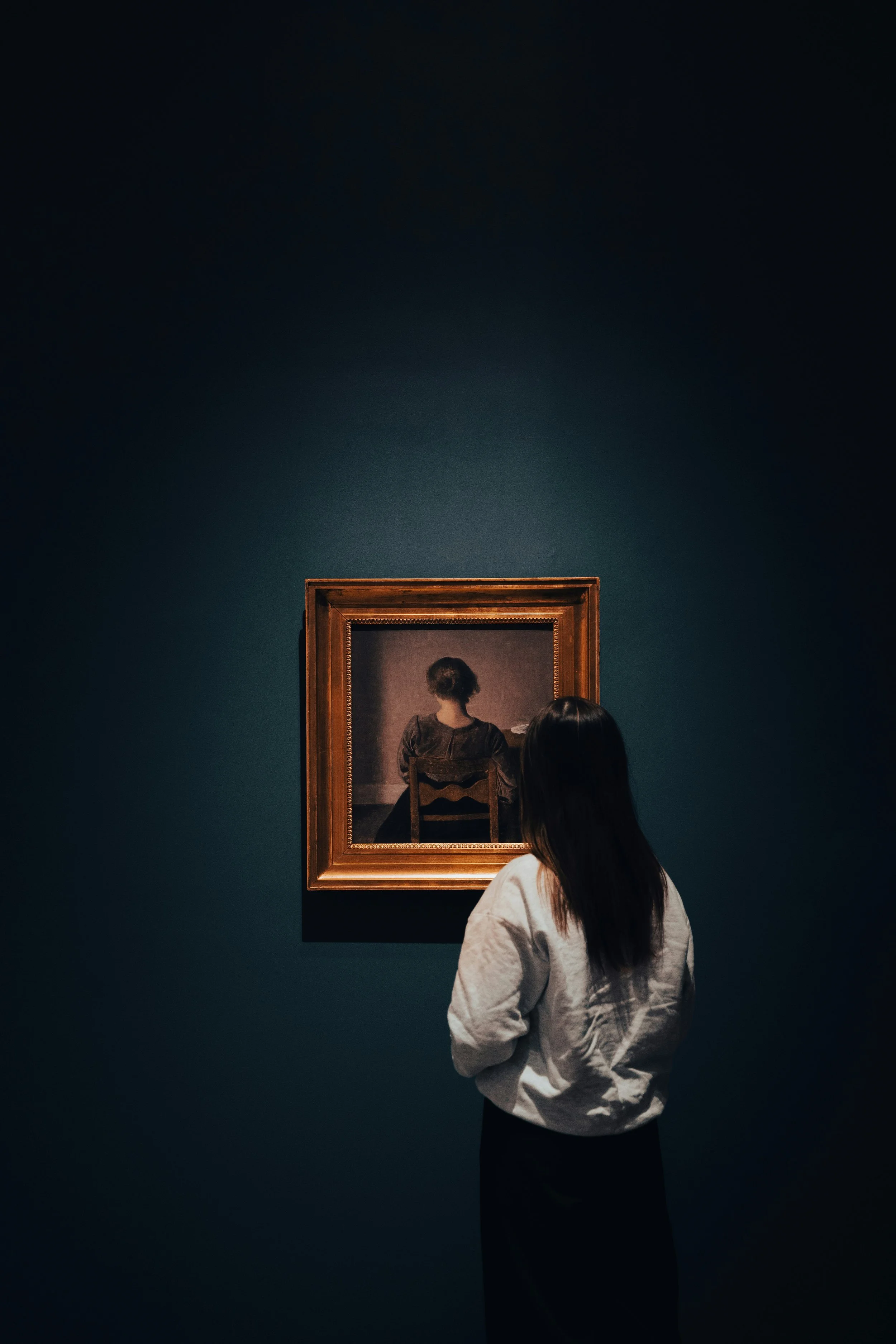 A person standing quietly in front of a framed painting in a museum, reflecting on identity, memory, and inner belonging in a contemplative space.