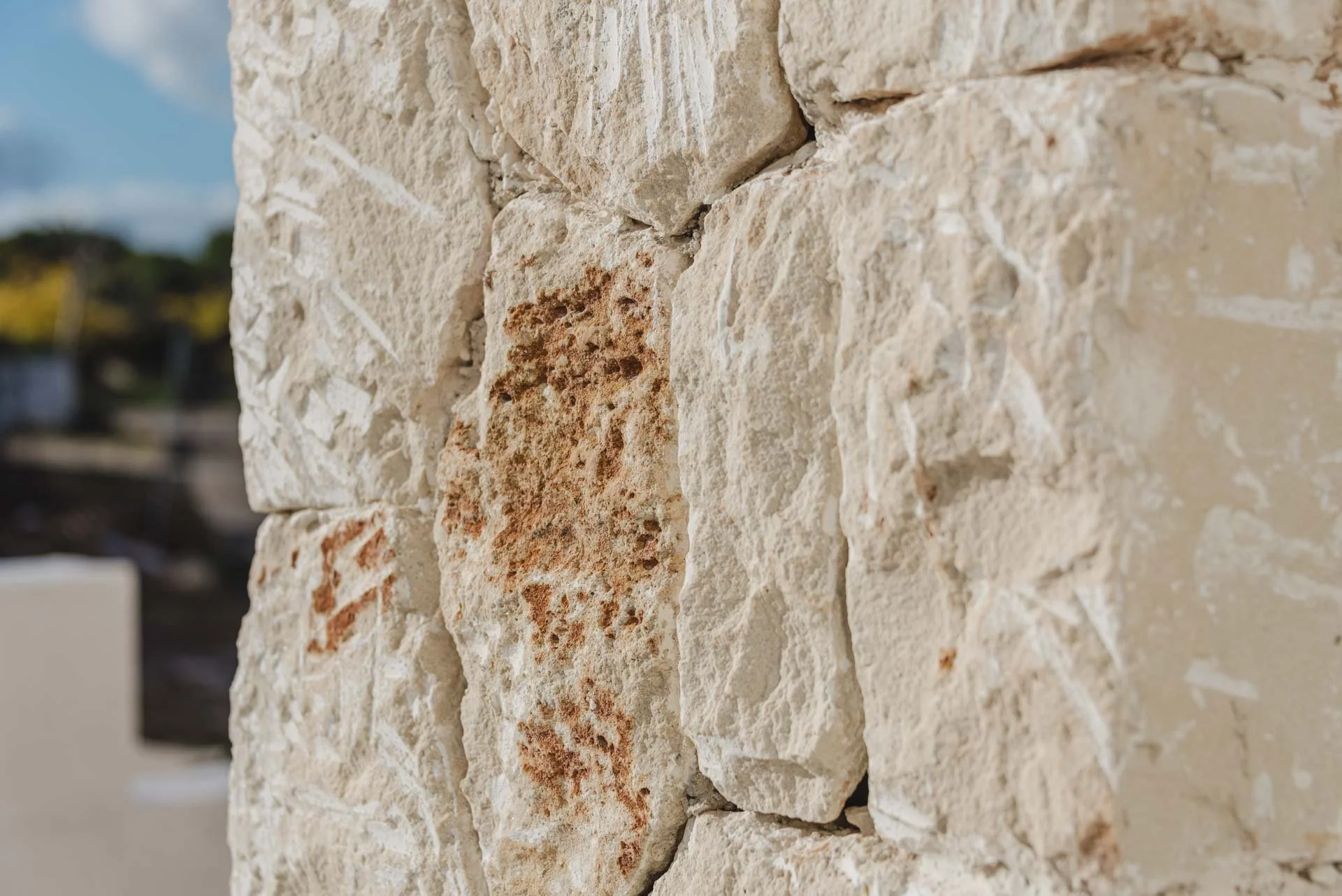 Close-up of a textured stone wall with rough, beige and reddish stones.