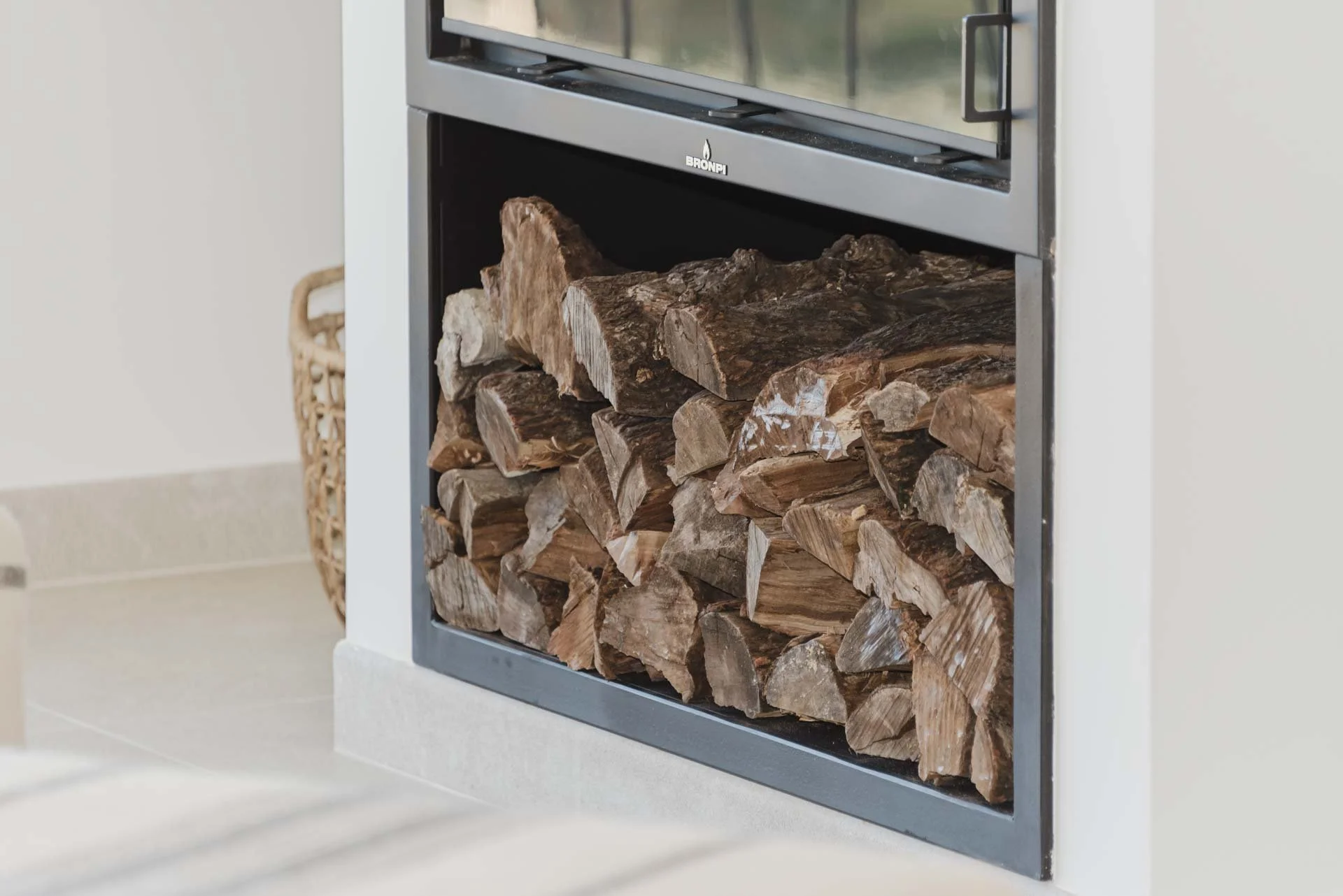 Stacked firewood stored inside a built-in fireplace with a metal frame.