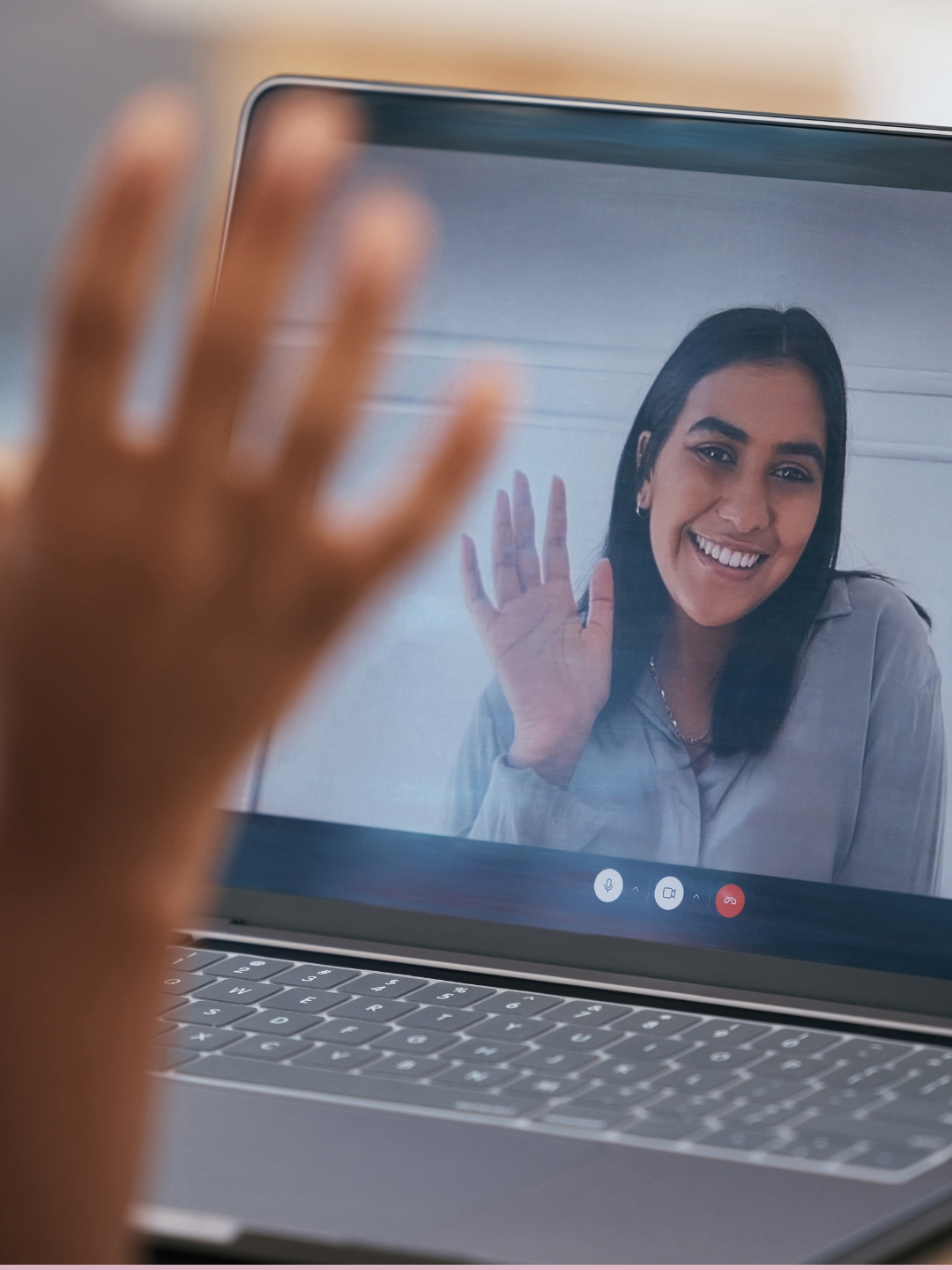 Bild zeigt eine Frau im Videocall, die winkt. Die Person die vor dem Laptop sitzt winkt ihr zurück.
