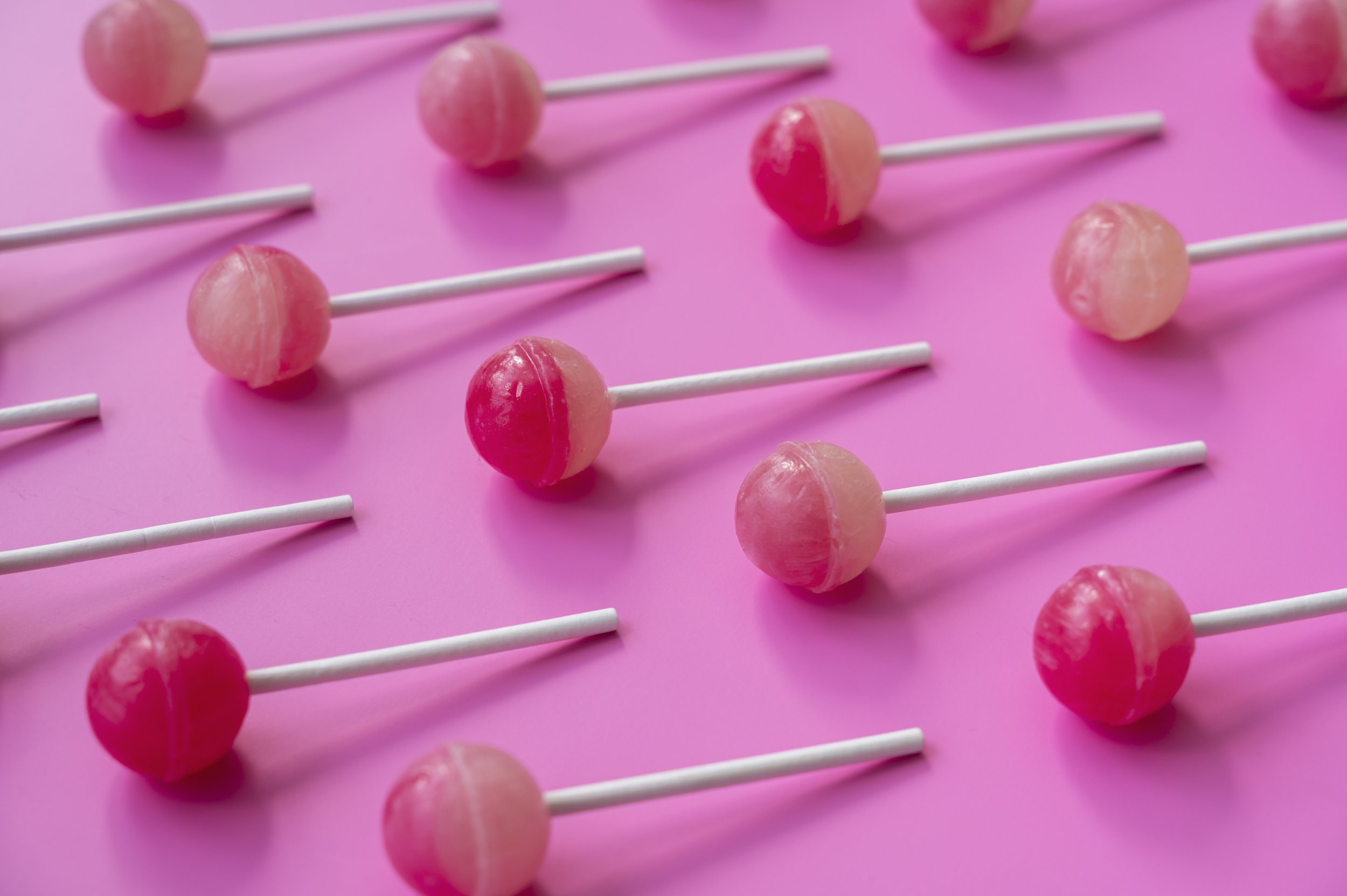 Non-vegan milk filled lollipops collage, pink background