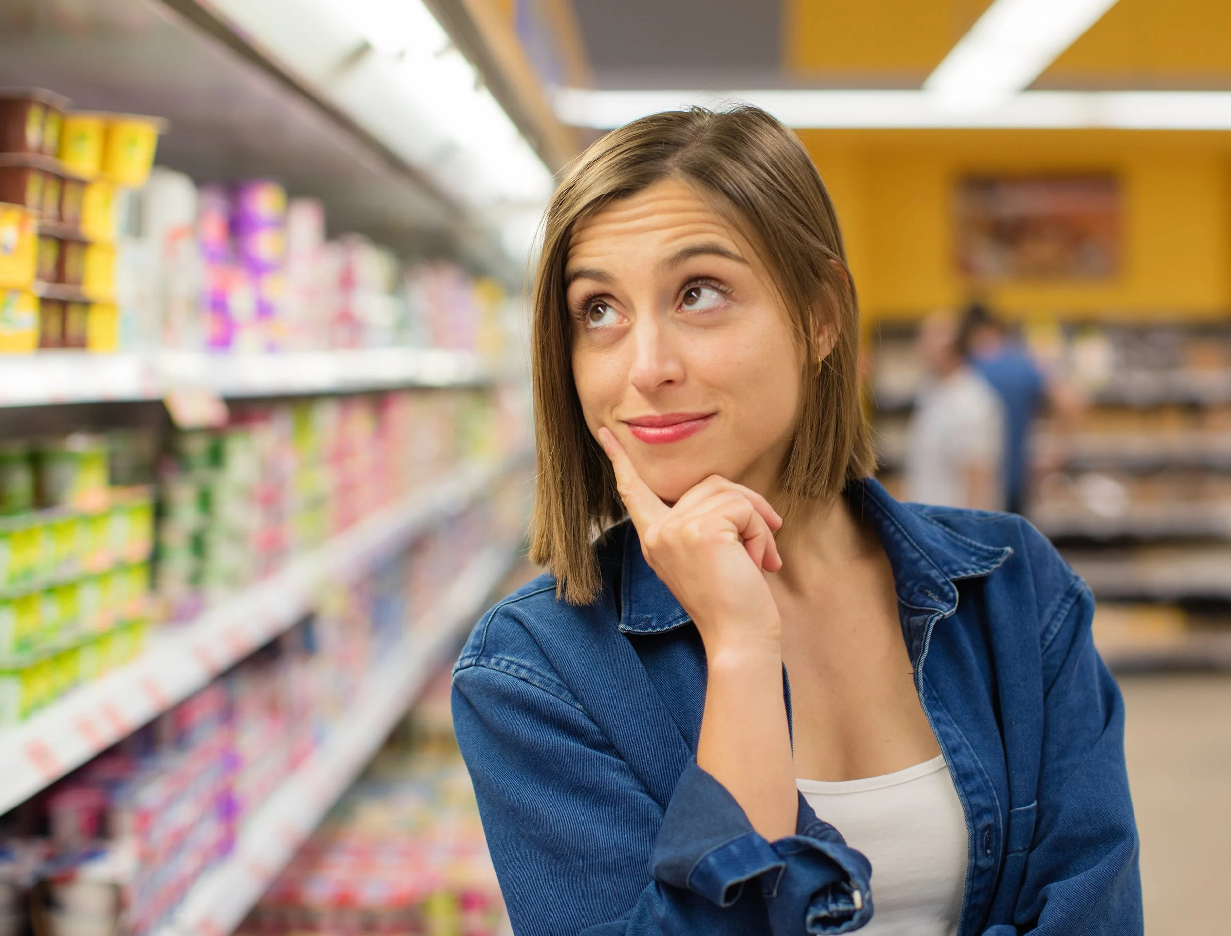 Woman checking for ingredients that can make candy non-vegan, inside a supermarket