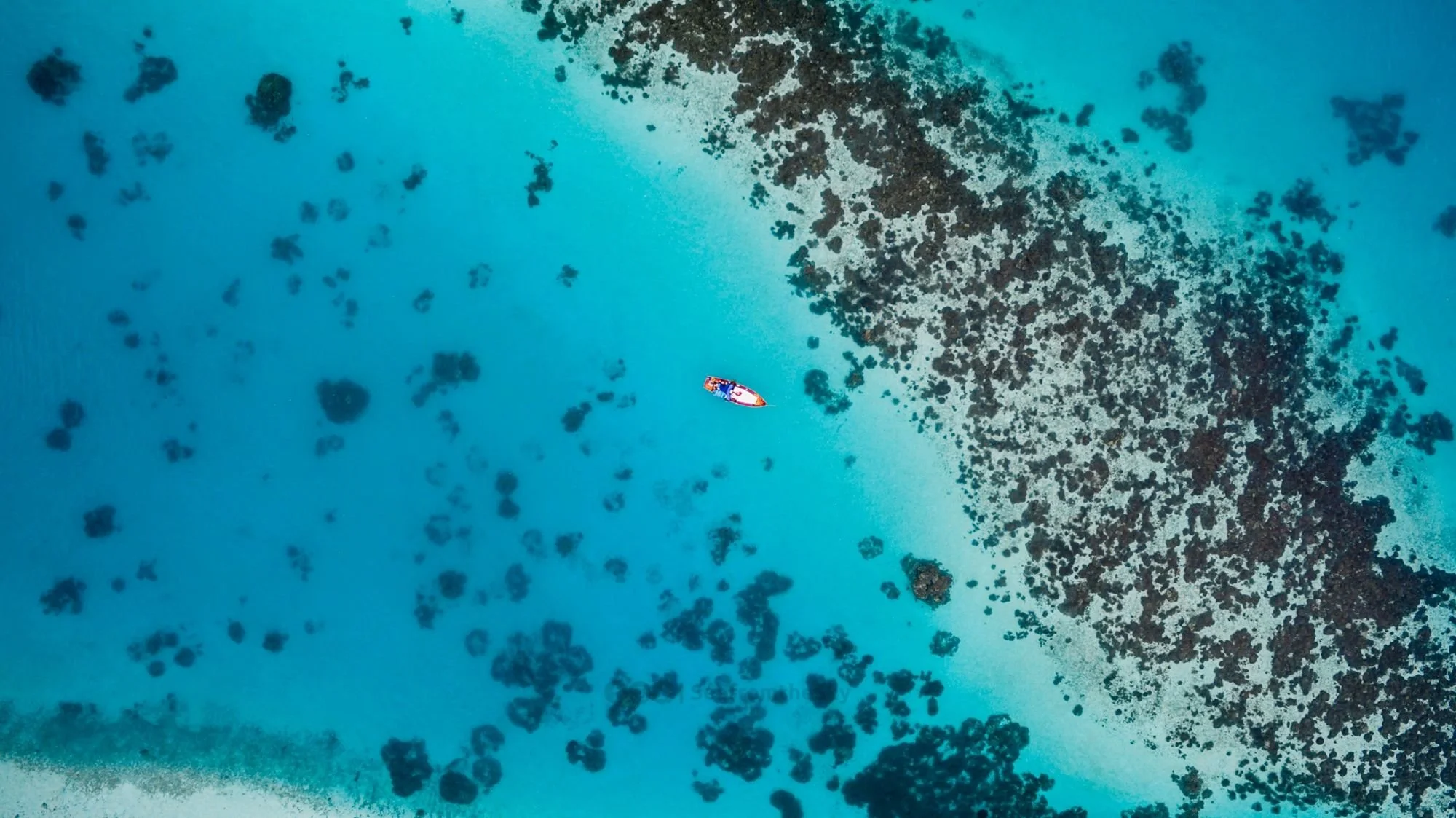 Aerial view of a deep blue channel cutting through Huvadhu Atoll, Maldives