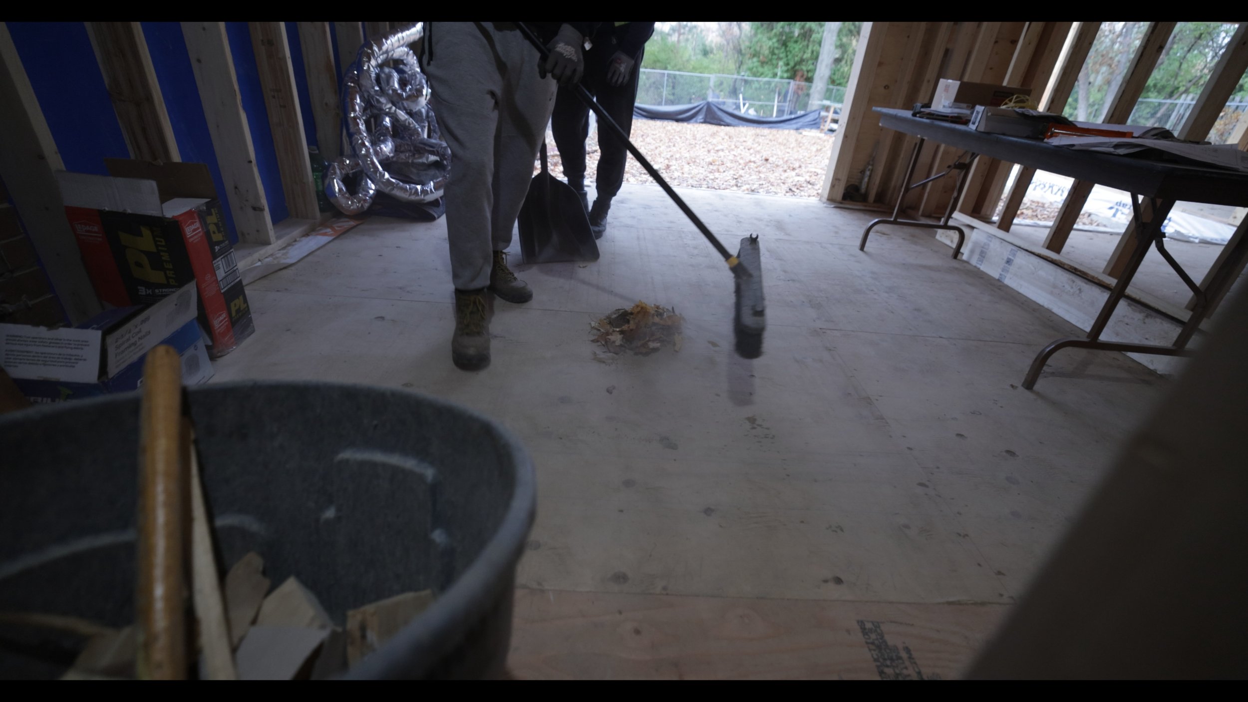 Construction worker demolishing a wall with a sledgehammer inside a building under construction.