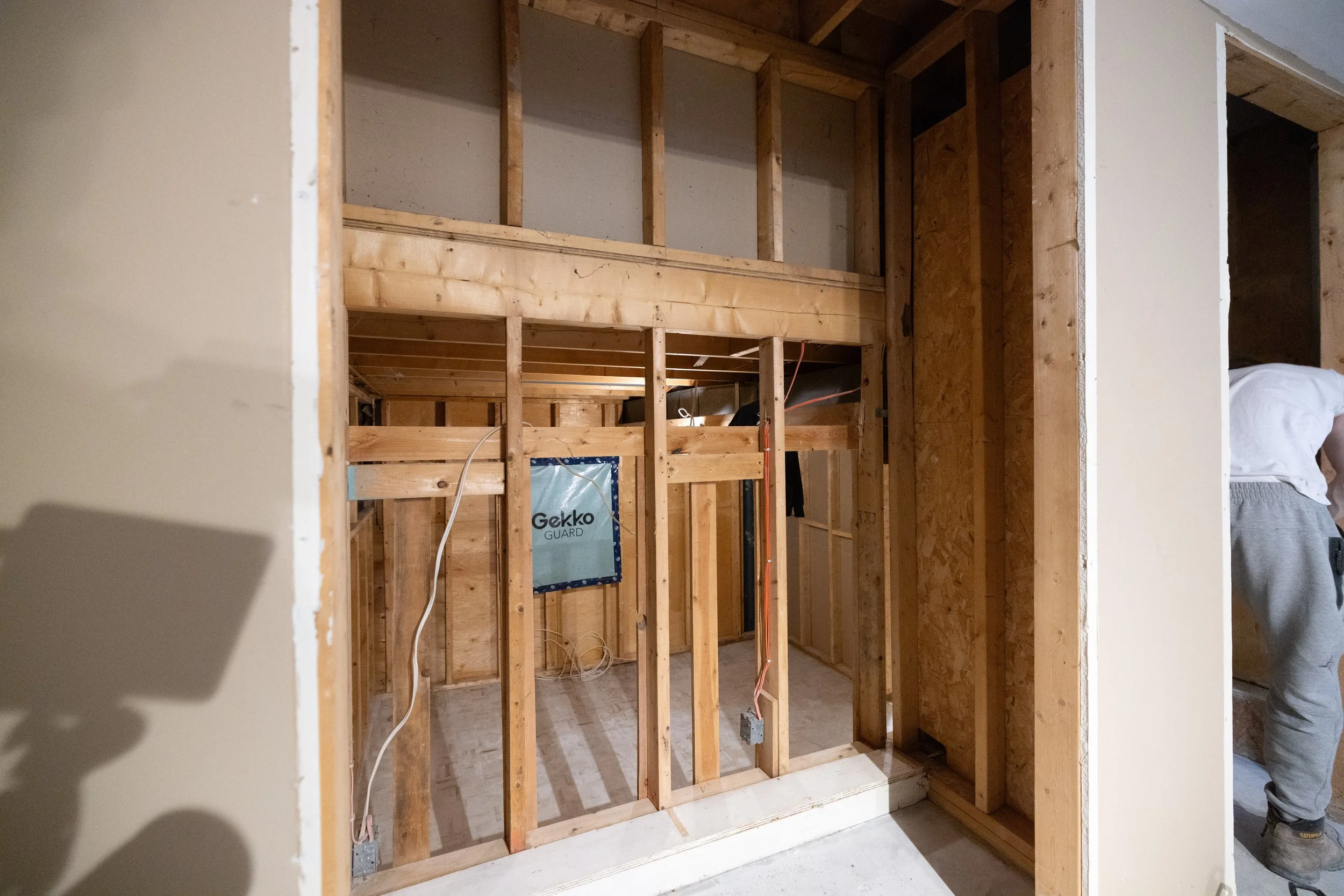 Interior view of a partially built room with exposed wooden framing and electrical wiring, showing unfinished walls and structure.