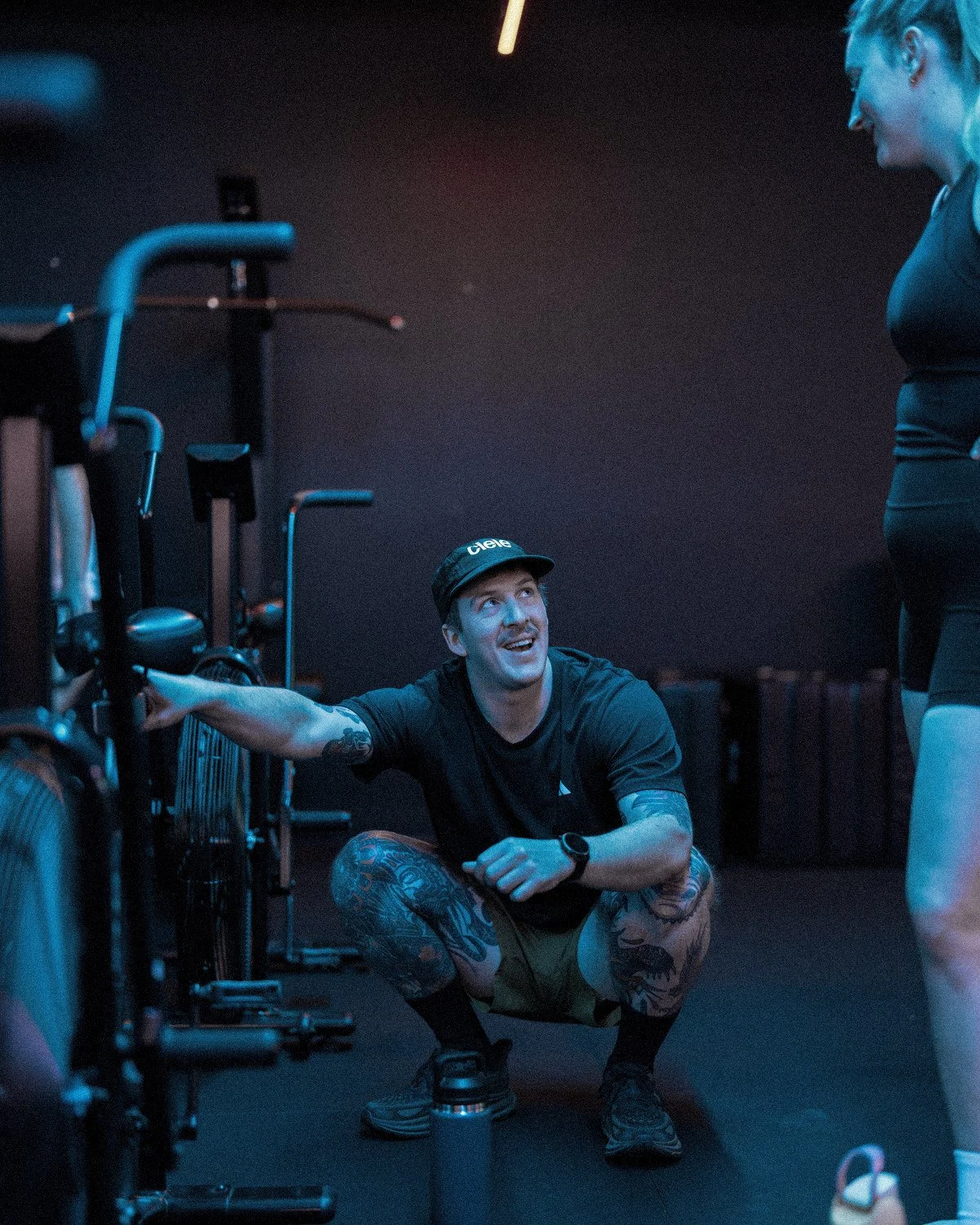 Two people talking during a personal and group training session in a gym, with the caption "Personal & Group Training" in blue text.