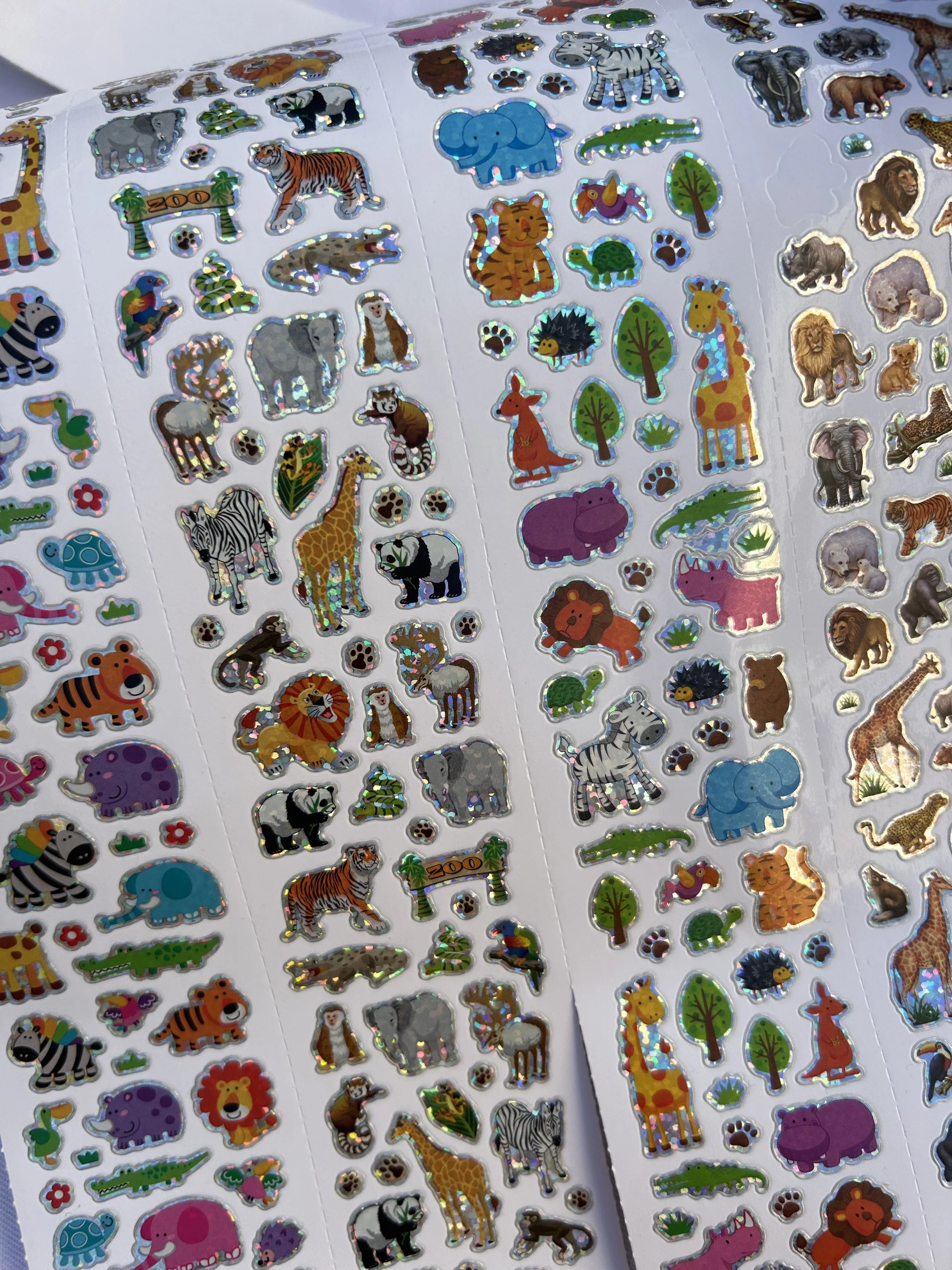 Aufkleberbogen mit bunten Tiermotiven, darunter Löwen, Giraffen, Elefanten, Zebras, Tigern, Pandas, Schildkröten, Vögel und andere Tiere, auf mehreren weißen Bögen.