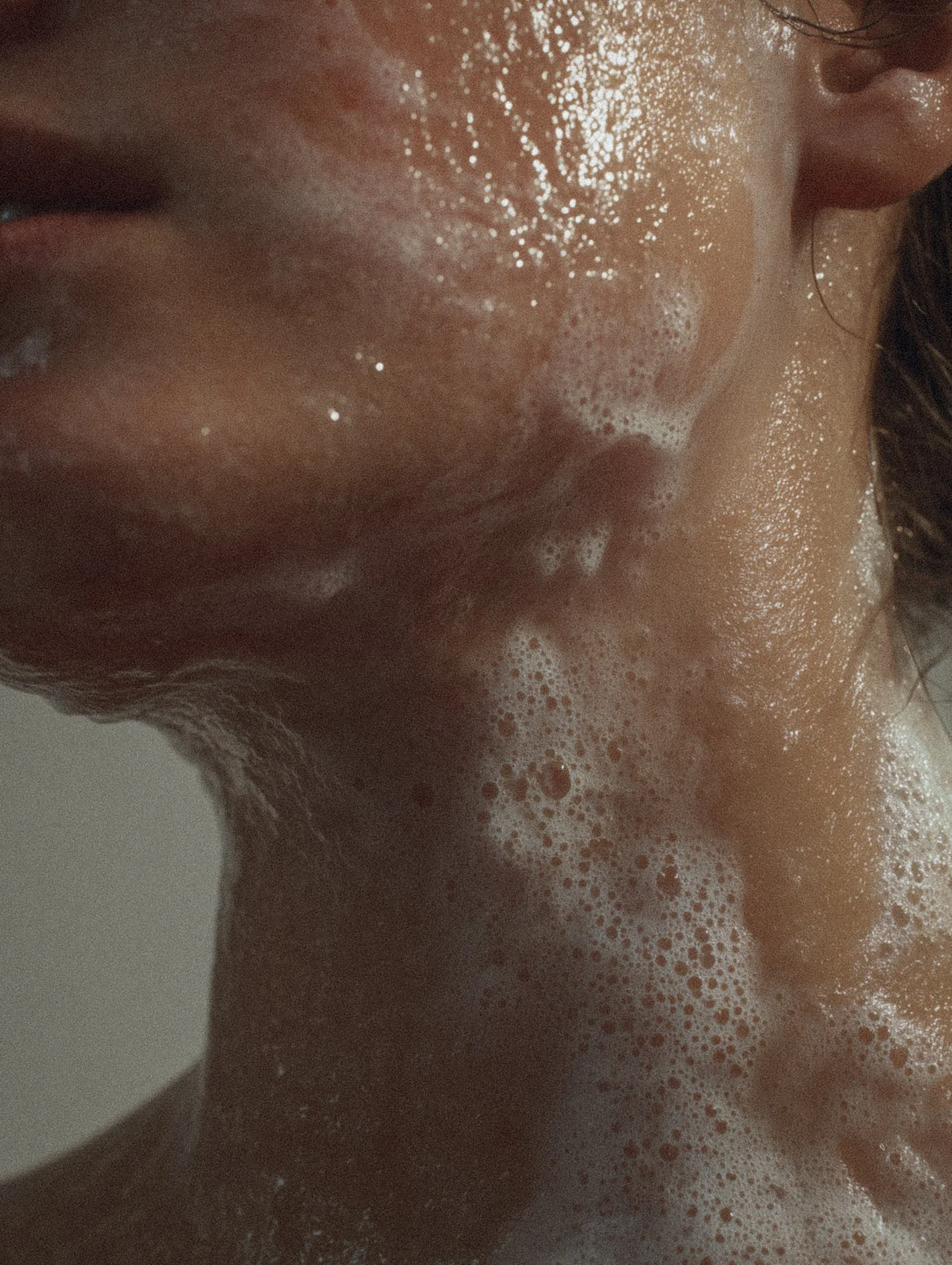 Close-up of a person's face and neck covered in soap suds during a shower or bath.