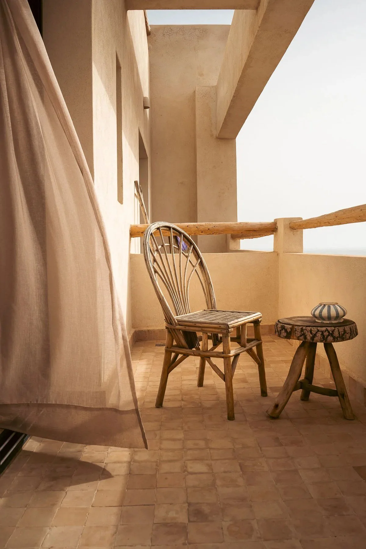 Rincón del balcón con silla de fibras naturales.