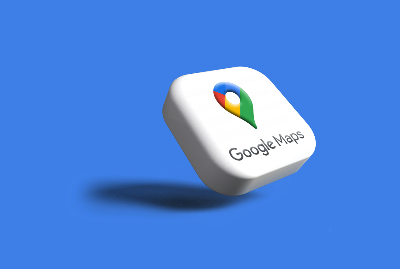 The image shows a 3D-rendered, slightly rounded, white square with the colorful Google Maps pin logo on top. The text "Google Maps" is below the logo. The white square appears to be floating over a solid blue background and casts a shadow underneath 