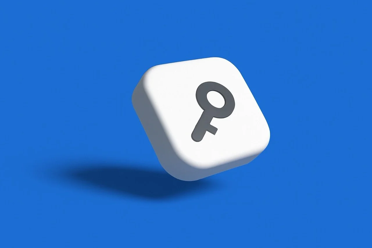 The image shows a white, rounded, square-shaped 3D object floating against a solid blue background. A dark gray key icon is depicted in the center of the white object. The object has a shadow beneath it.