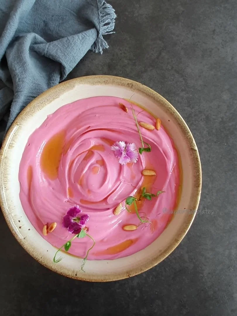 Plat ou bol avec une préparation rose, décoré avec des fleurs, des graines et de la sauce caramélisée ou au caramel.