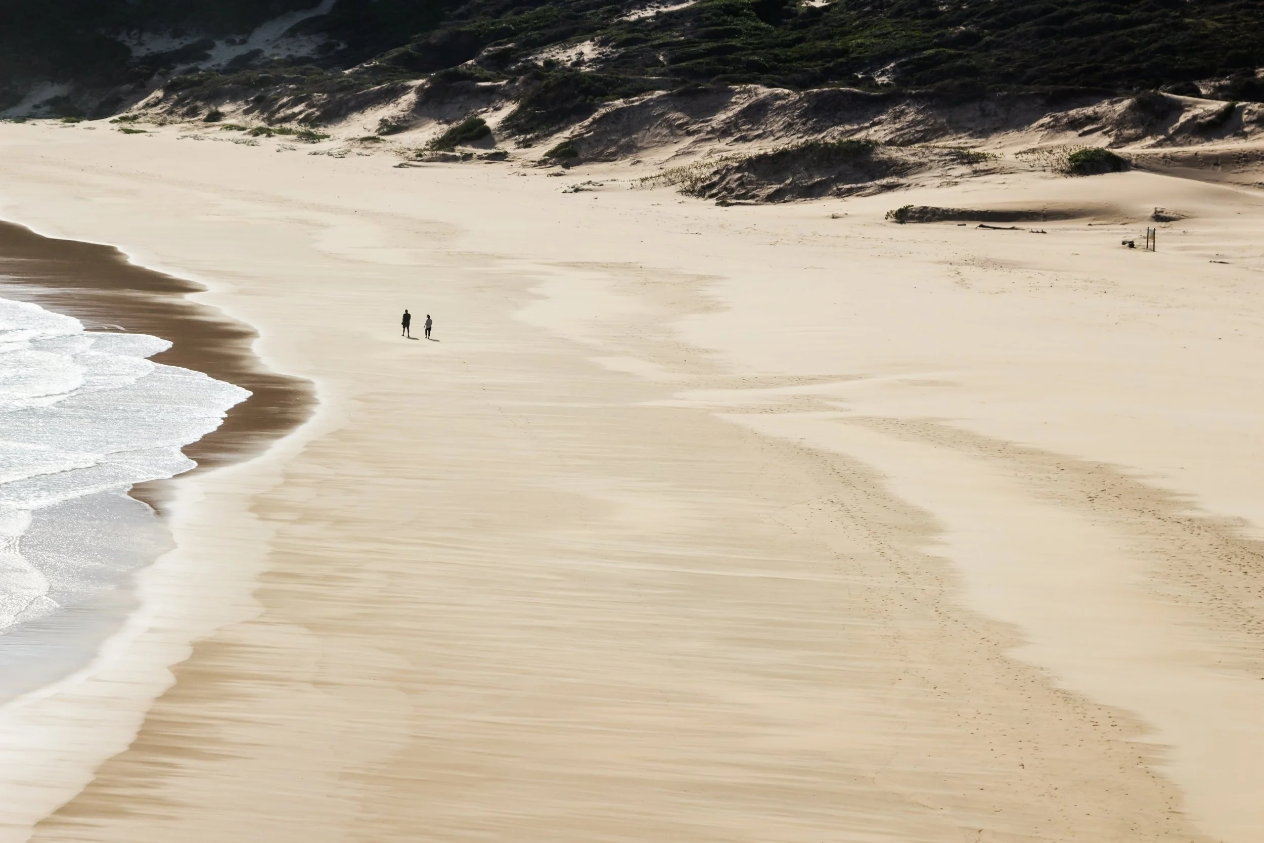 aerial-shot-two-people-walking-beautiful-beach-by-sea.jpg