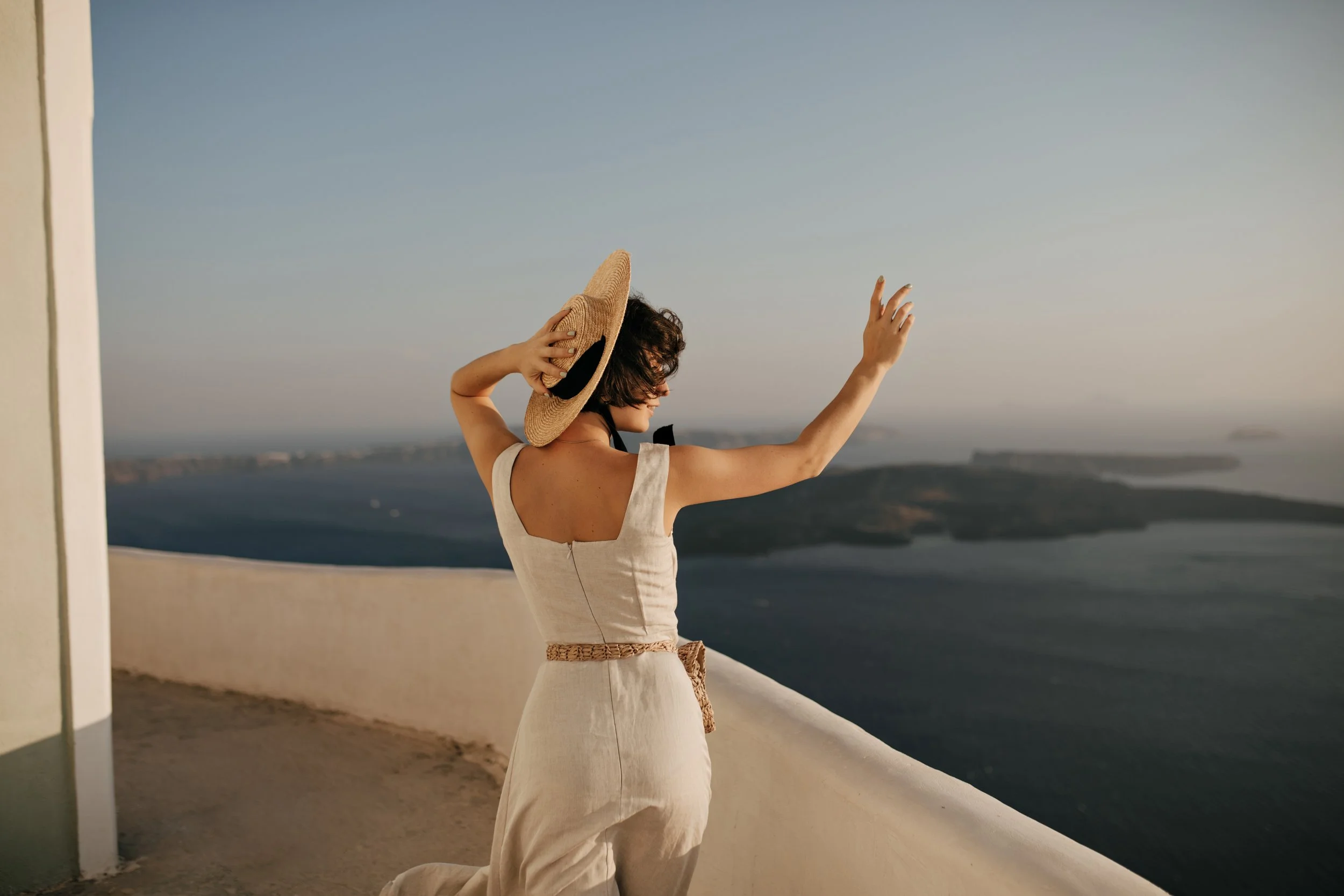 brunette-curly-woman-elegant-beige-dress-straw-widebrimmed-hat-enjoys-sunny-weather-beautiful-sea-view.jpg