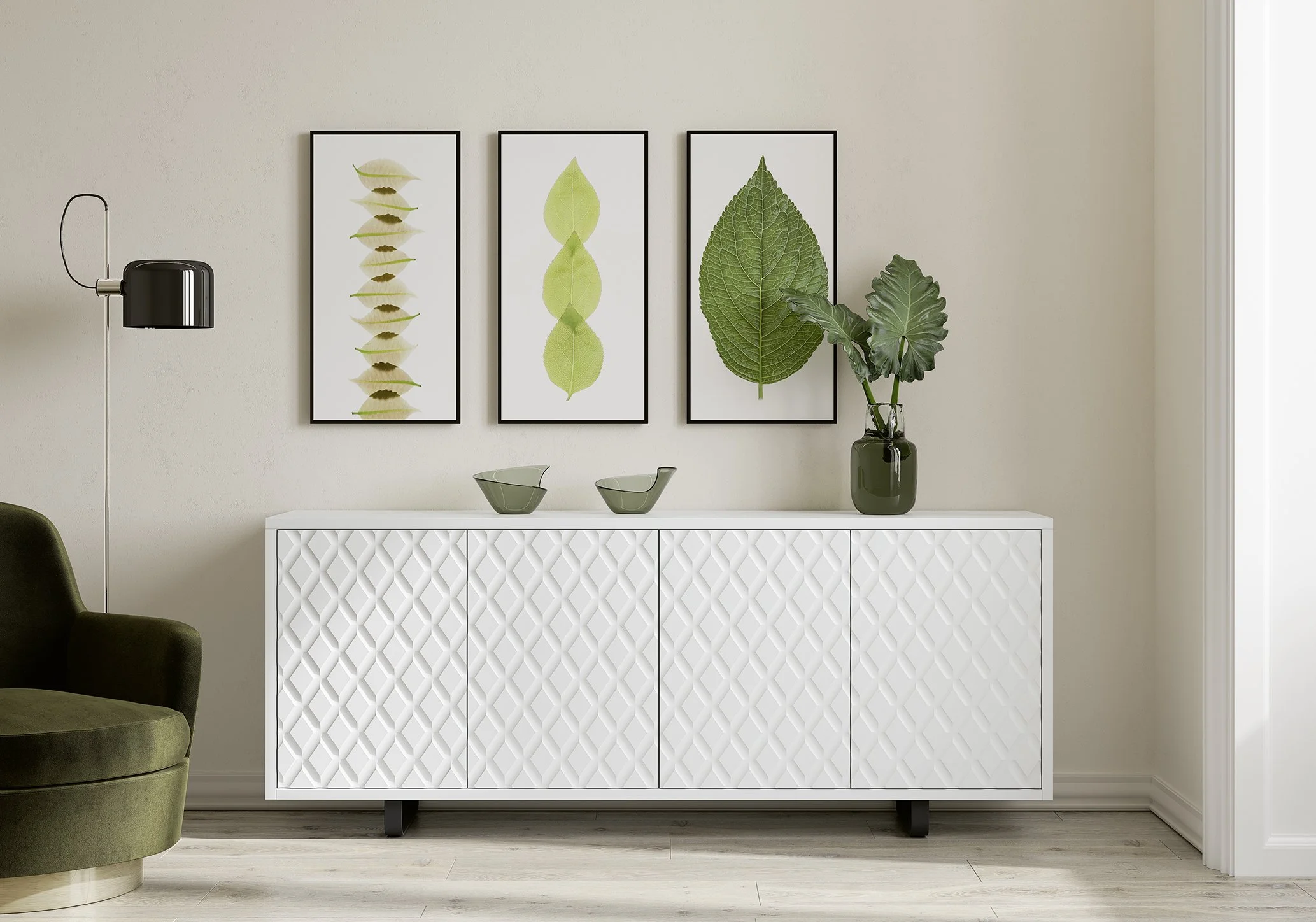 Weiße Sideboard mit geometrischem Muster, oben grüner Pflanzenstrauß in einem schwarzen Vase, drei Wandbilder mit grünen Blättern, dunkle Stehlampe und grüner Sessel