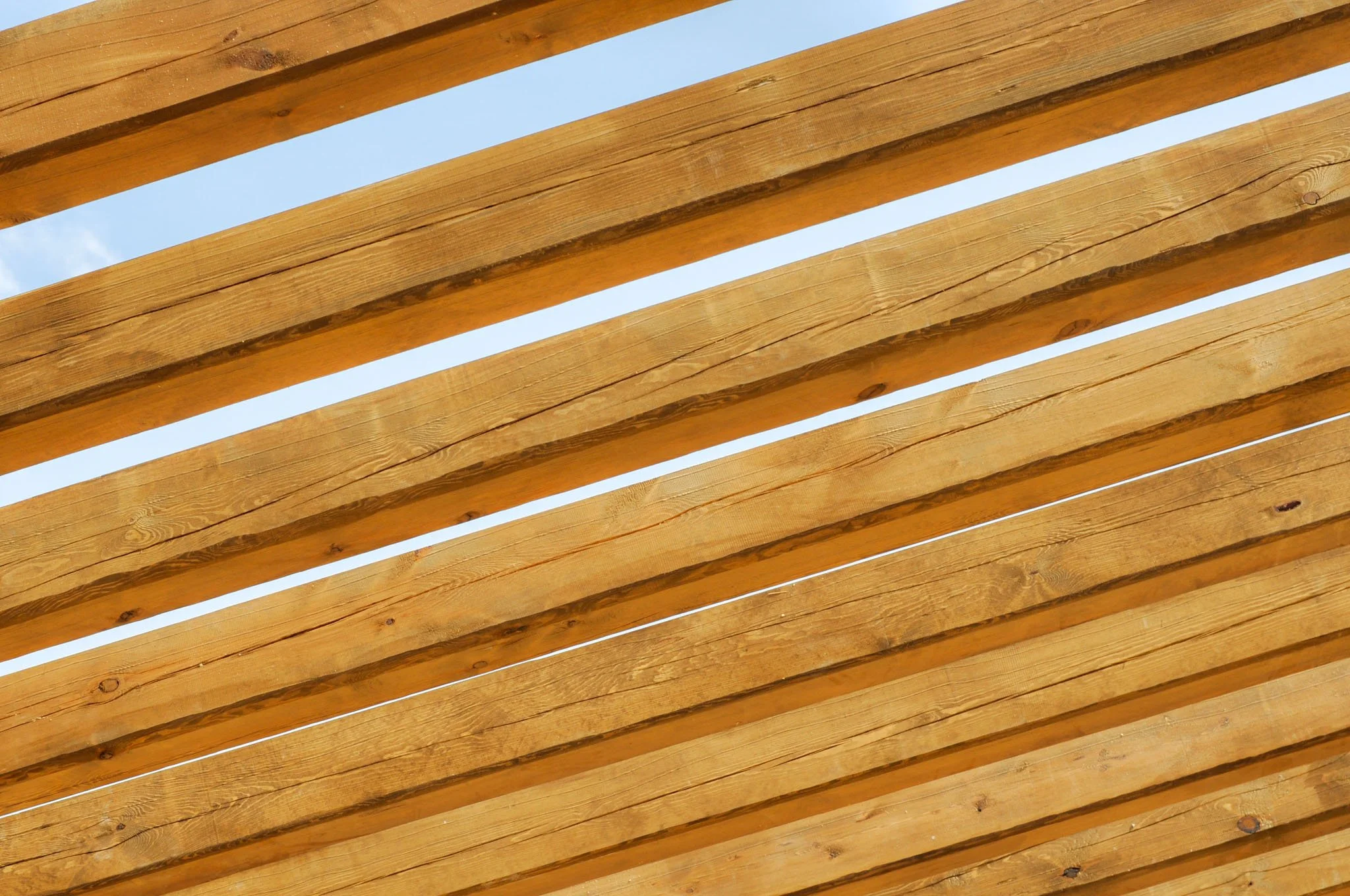 Perspectiva de lamas de madera colocadas en paralelo, con el cielo visible en los espacios entre ellas.