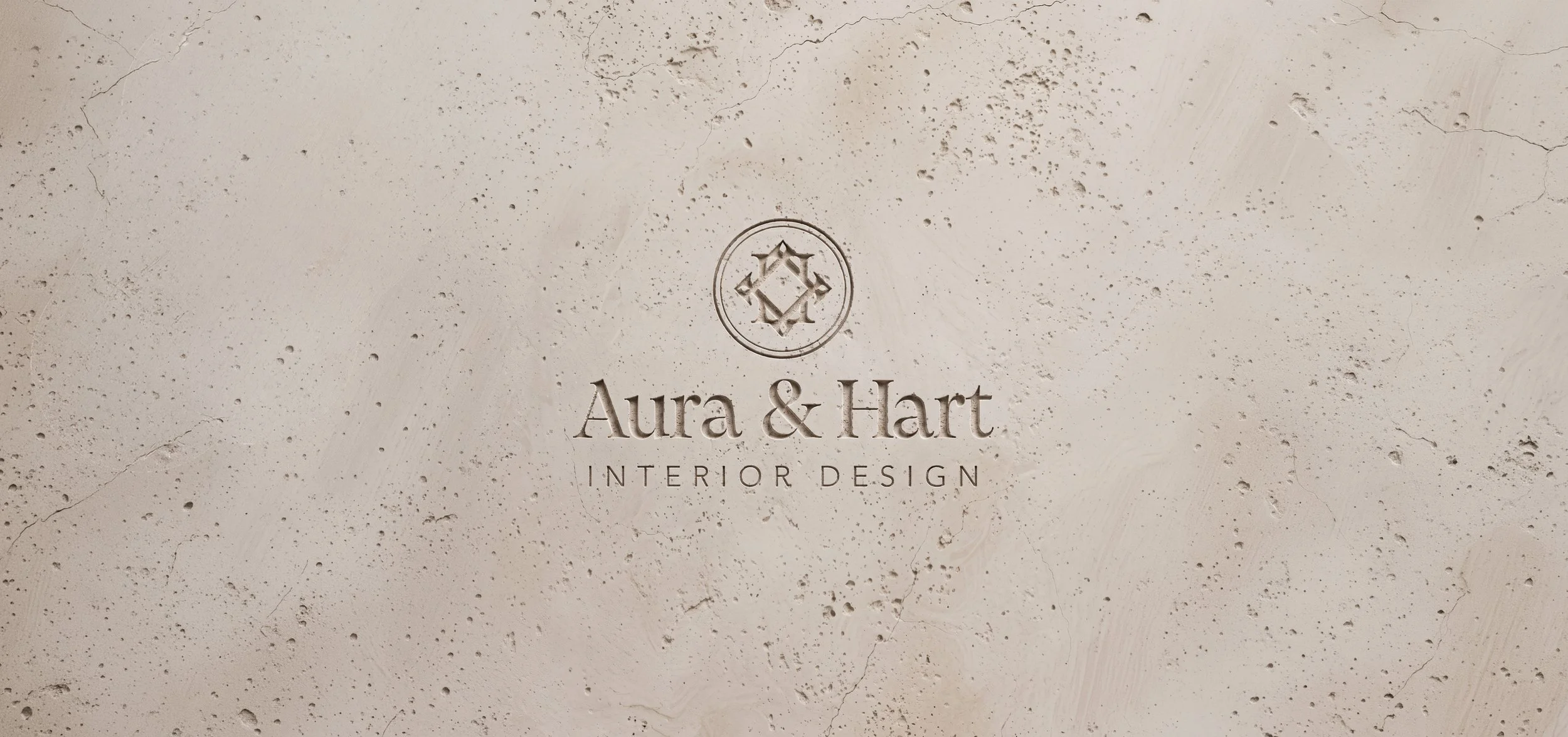 Embossed logo for Aura & Hart Interior Design on a beige textured surface.
