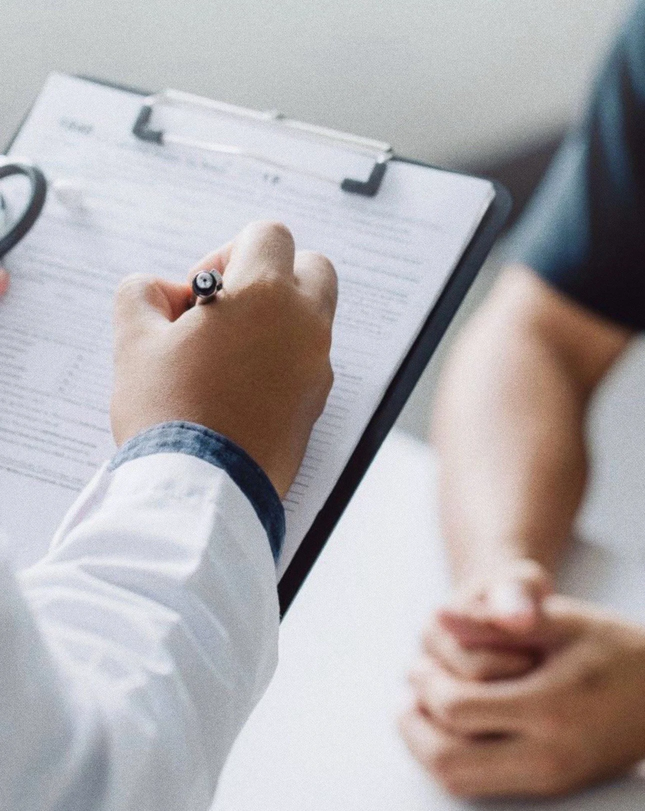 Henkilö kirjoittaa paperille yhdellä kädellä ja toisen käden sormi on koholla, lähellä paperia.