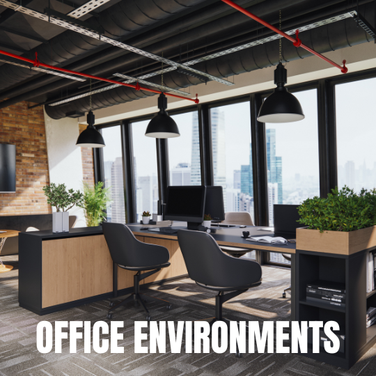 Modern office interior with large windows offering city views, wooden desks, black chairs, hanging lights, and lush green plants. Text reads "Office Environments."
