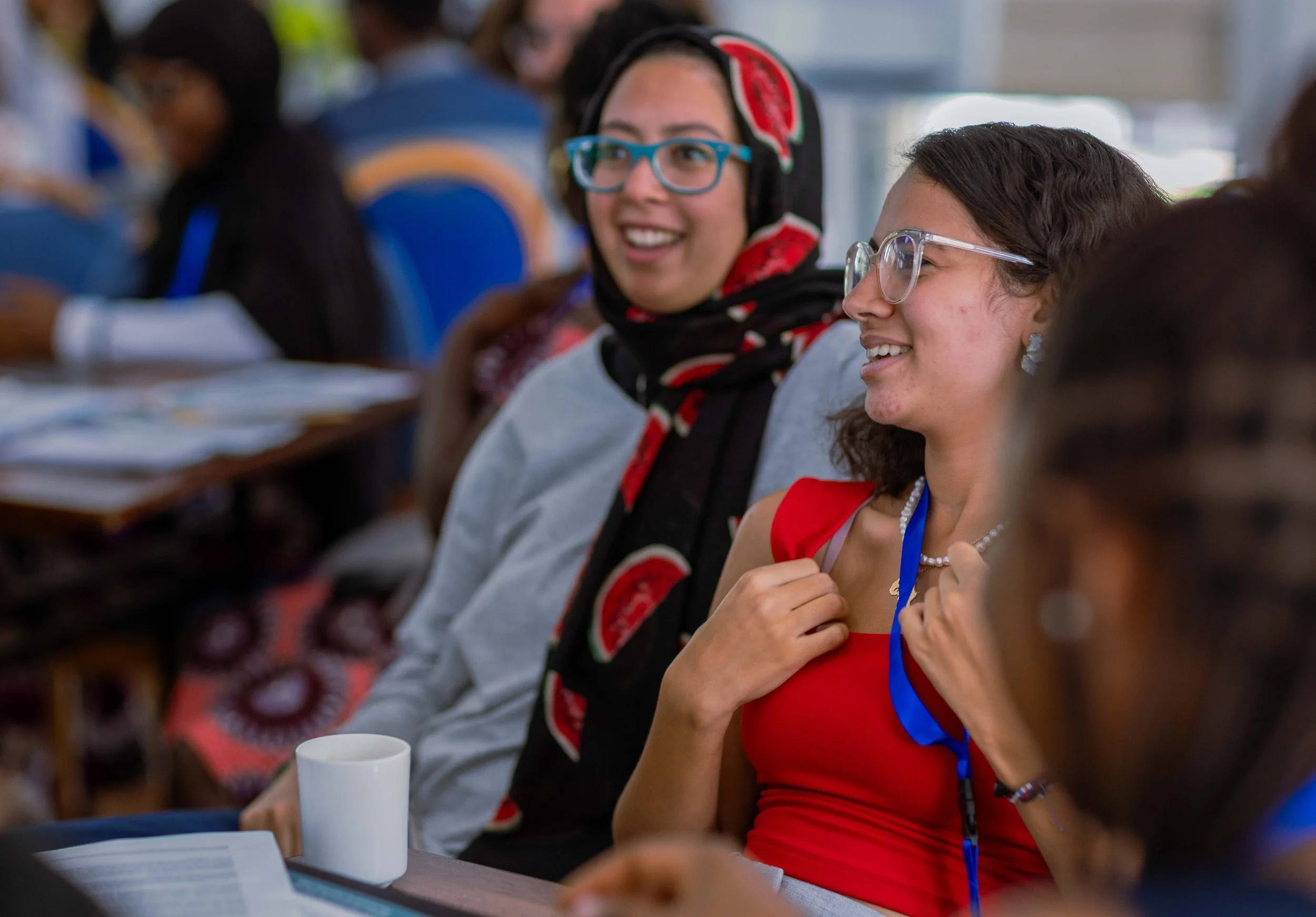 Group of women sitting at the Climate Simulation Games, smiling and engaging, with notebooks and cups on the table.