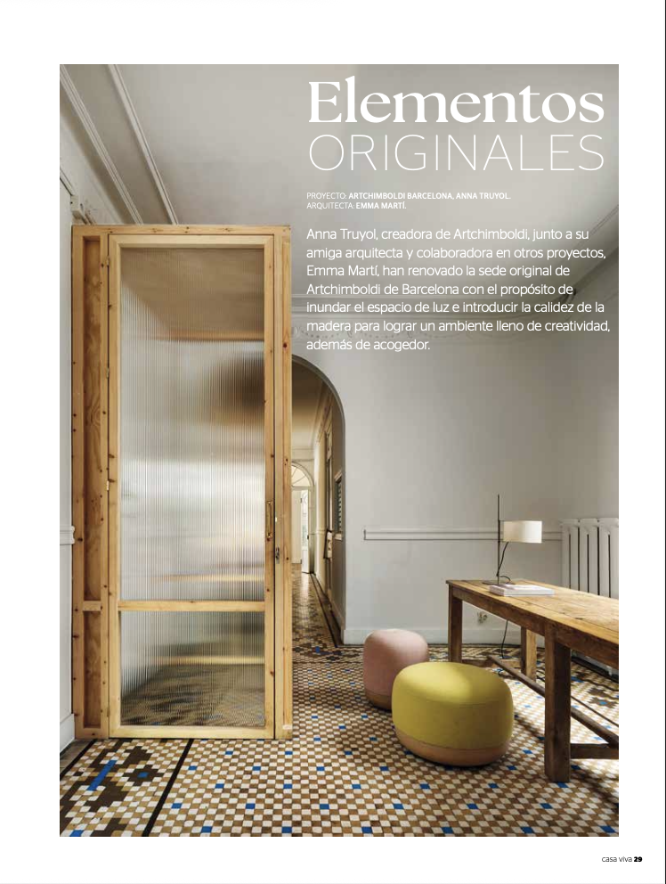 Interior de una casa con mobiliario de madera y silla de colores, piso de mosaico y pared blanca