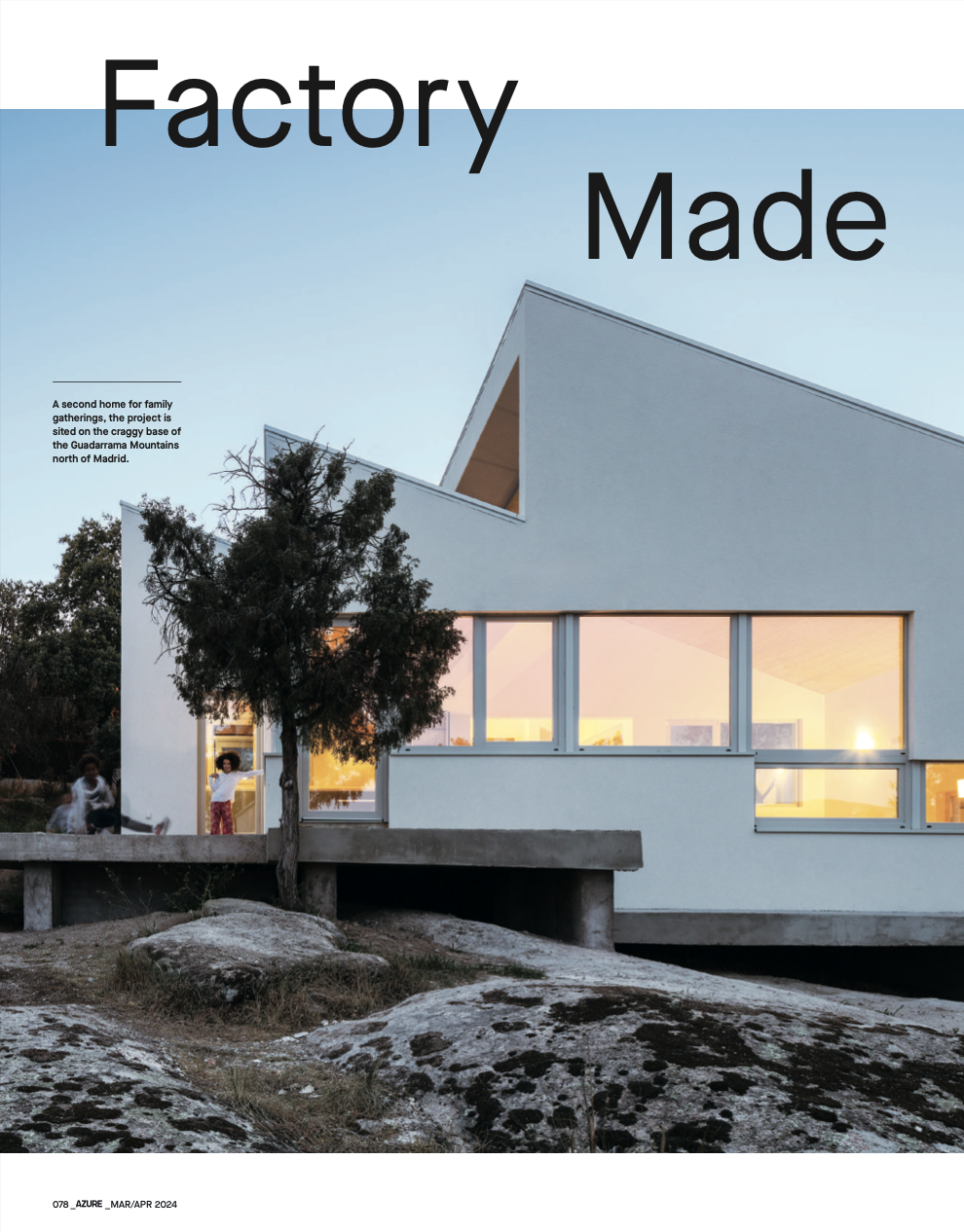 Una casa moderna en las montañas con grandes ventanales, iluminada en el interior, y dos niños jugando fuera