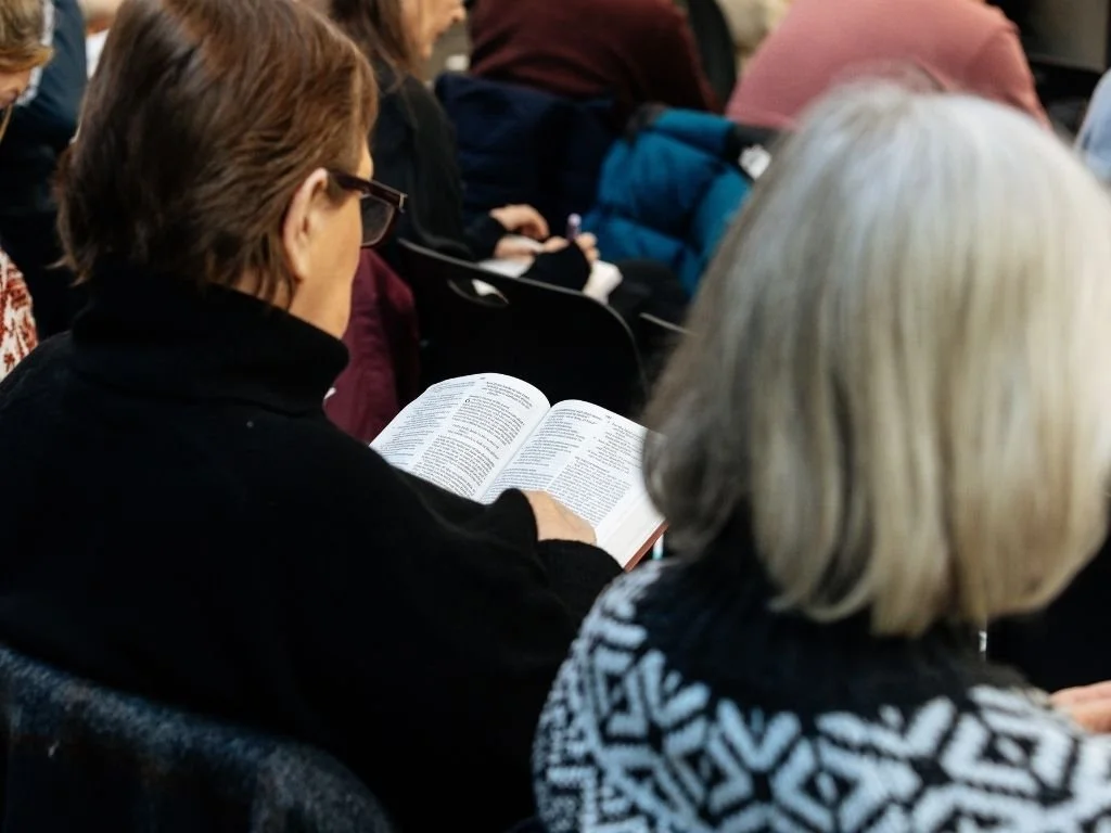 Woman looking at an open Bible while sitting in a congregation