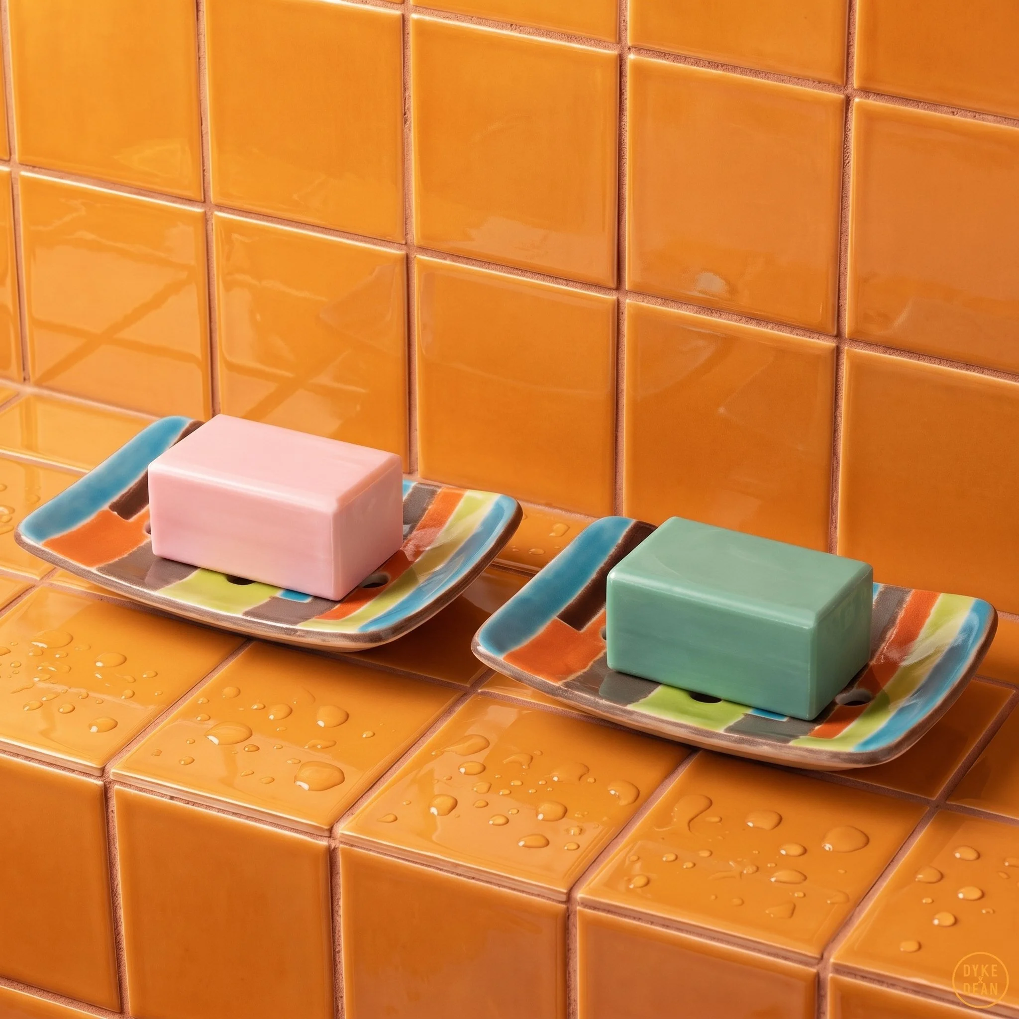 Des carreaux de mur orange brillant avec de la texture en particulier des gouttes d'eau sur certains. Dans le coin inférieur droit, il y a un logo orange avec le texte "DIXE" au-dessus du texte "NEAN".